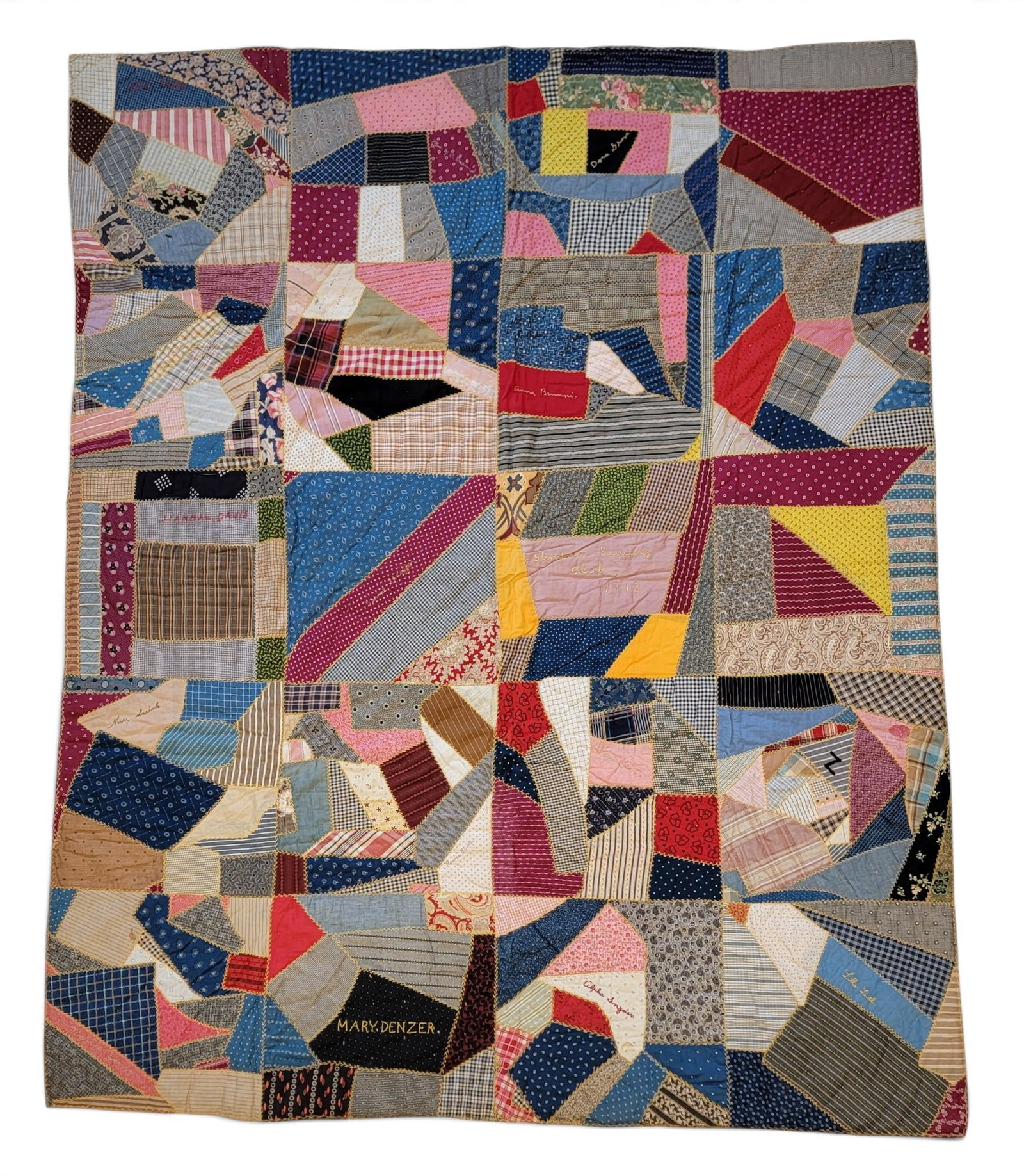 QUILT MADE BY THE SLIMTOWN SEWING CLUB, 1913: Crazy quilt with twenty pieced squares, and with turkey track stitching and the club name and seventeen members embroidered. 85" by 67". Provenance: the collection of the late Dr. Virginia Gunn,