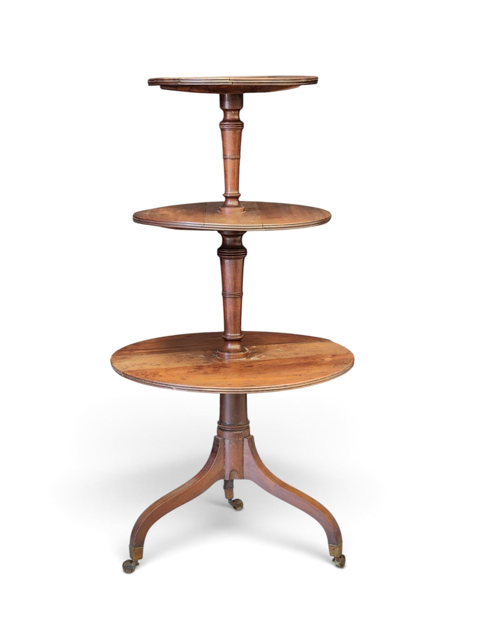 GEORGE III DUMBWAITER: English, early 19th century, mahogany. Three-tiered waiter, each tier round with drop leaves, and on a tripod base with original brass casters. 47" high, 23.5" diameter at the widest. Provenance: an