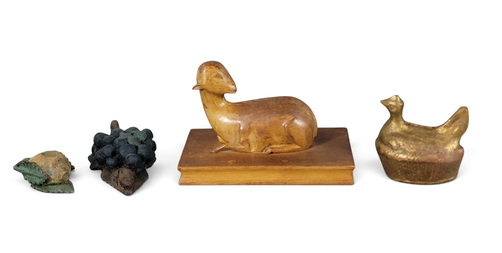 COLLECTION OF FOLK ART ANIMALS AND FRUIT: 19th-20th century. Includes a folksy carved lamb on a book with worn original finish, 9" long; a painted pottery hen-on-nest bank, 4.5" high; and two carved and painted fruit, grapes are 6" long.