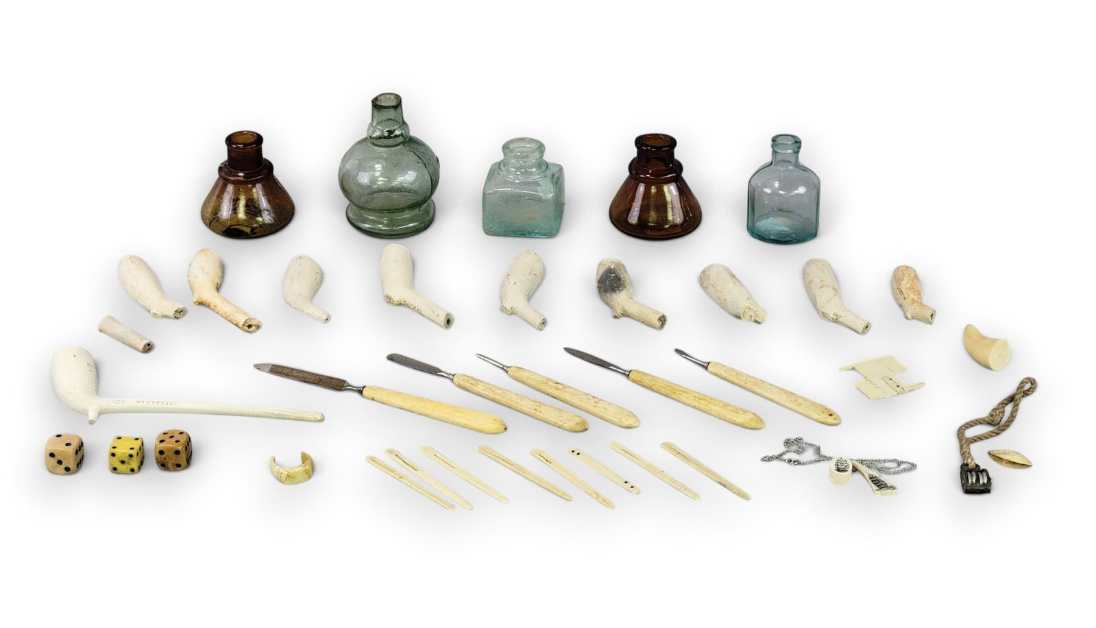 COLLECTION OF EARLY ACCESSORIES: American, 19th century. Includes five glass inkwells, a collection of clay pipes/fragments, and various bone accessories, including knives and dice. Provenance: an Ohio collection. NOTE: We are happy