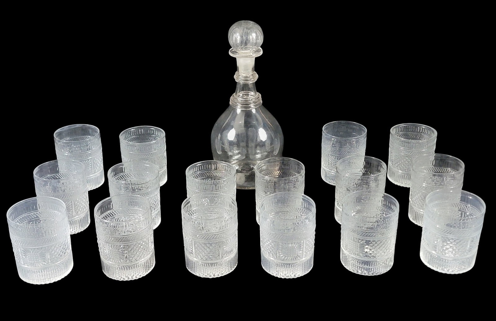 GLASS DECANTER AND TUMBLERS: Includes an American, 19th-century blown decanter with applied rings, 10.5" high; together with a set of 16 MMA reproduction three-mold tumblers, 3.25" high. Provenance: the collection of Marci and De