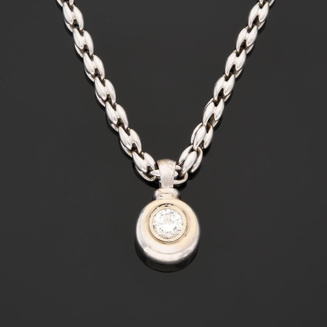 PENDENTIF en or gris, serti clos d'un diamant: PENDENTIF en or gris, serti clos d'un diamant rond pesant 1,05 ct. Il est retenu par une chaîne d'or gris, signée Chimento. Dimensions de la pierre : 6,68 - 6,78 x 3,93 mm. Longueur de la ch