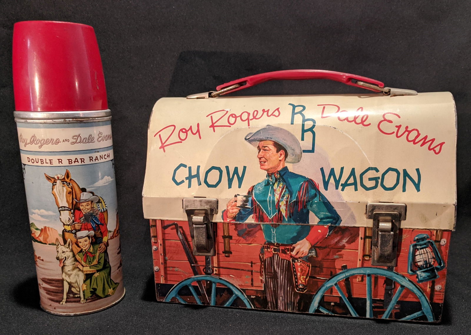 Roy Rogers Dale Evans Chow Wagon Domed LunchBox Thermos: Vintage Roy Rogers Dale Evans Chow Wagon Domed Metal Lunch Box & Thermos. The box, titled “Roy Rogers Dale Evans RR Chow Wagon.”, is in the shape of a Ponderosa chuck wagon and has an image of Roy