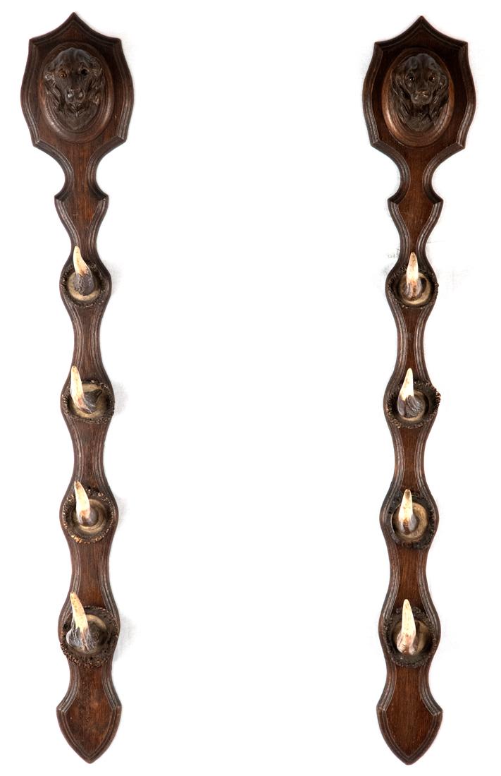 Black Forest Gun Rack with Carved Dogs and Horn: Two wall hanging walnut brackets surmounted with carved dogs (one dog is missing an eye) and inset horns for the holding of guns or other hunting implements made during the last quarter of the ninetee