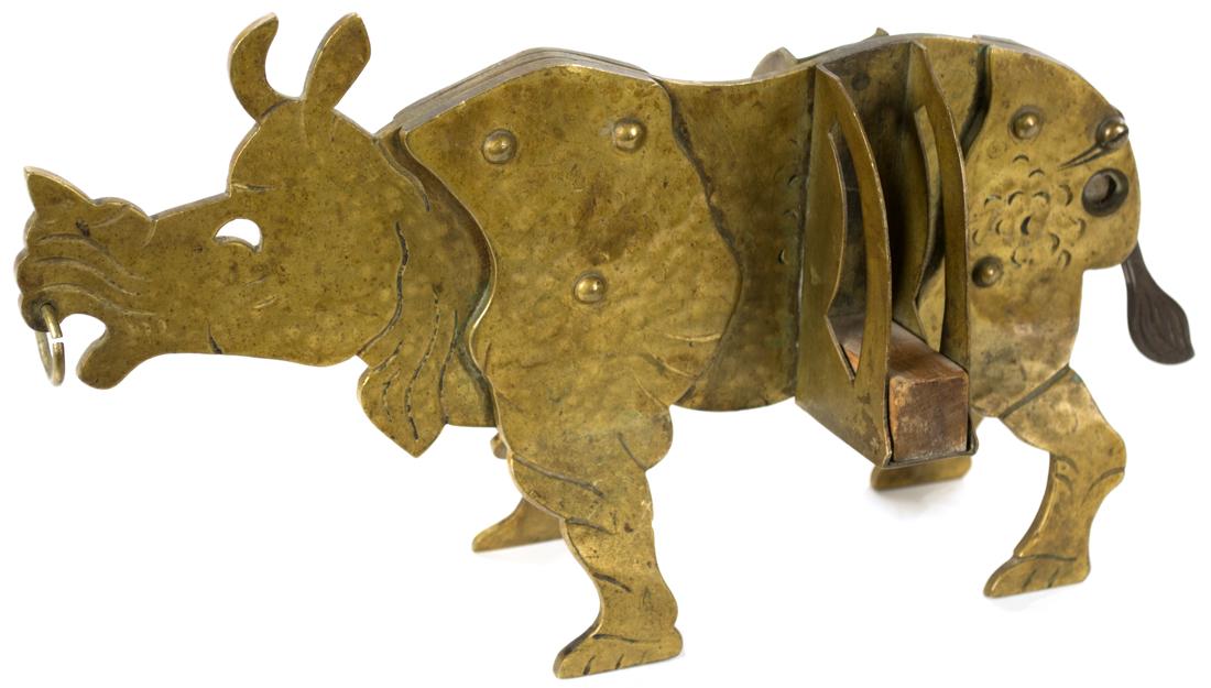 An Nineteenth-Century Rhinoceros Cigar Cutter: A unique and unusual cigar cutter in solid brass, which functions by raising and lowering the rhino's tail. The work is made out of solid, riveted brass and features a cigar rest on each side.