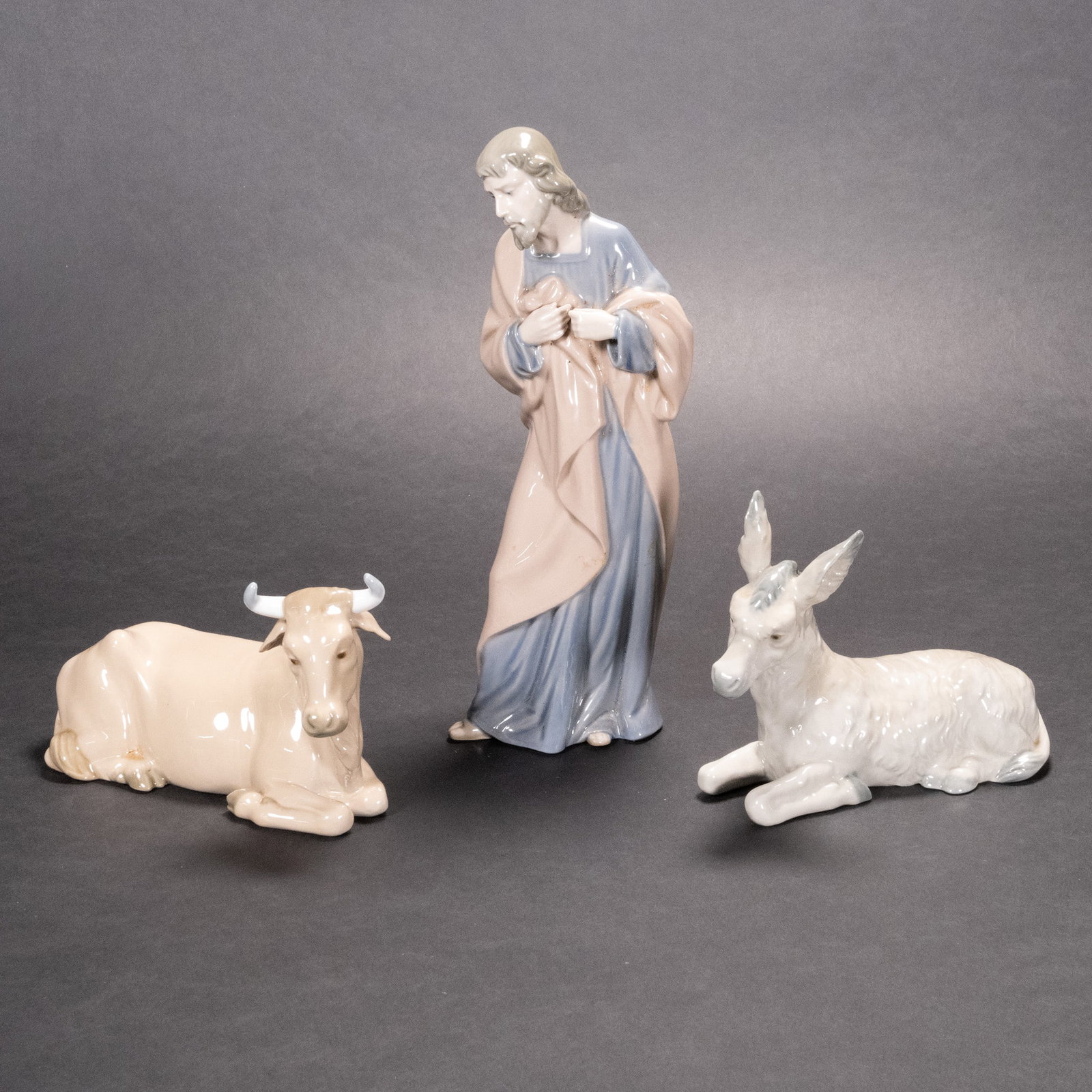 Lladro Lot Nativity Joseph Cow Bull Donkey Sculpture: Lladro Nao Nativity Joseph Cow Donkey Joseph 10" Tall Peering Downward Draped In A Salmon Colored Robe Covering A Blue Thobe Cow 7" L In Resting Posture Position Grey Donkey 6" In Overall Good Conditi