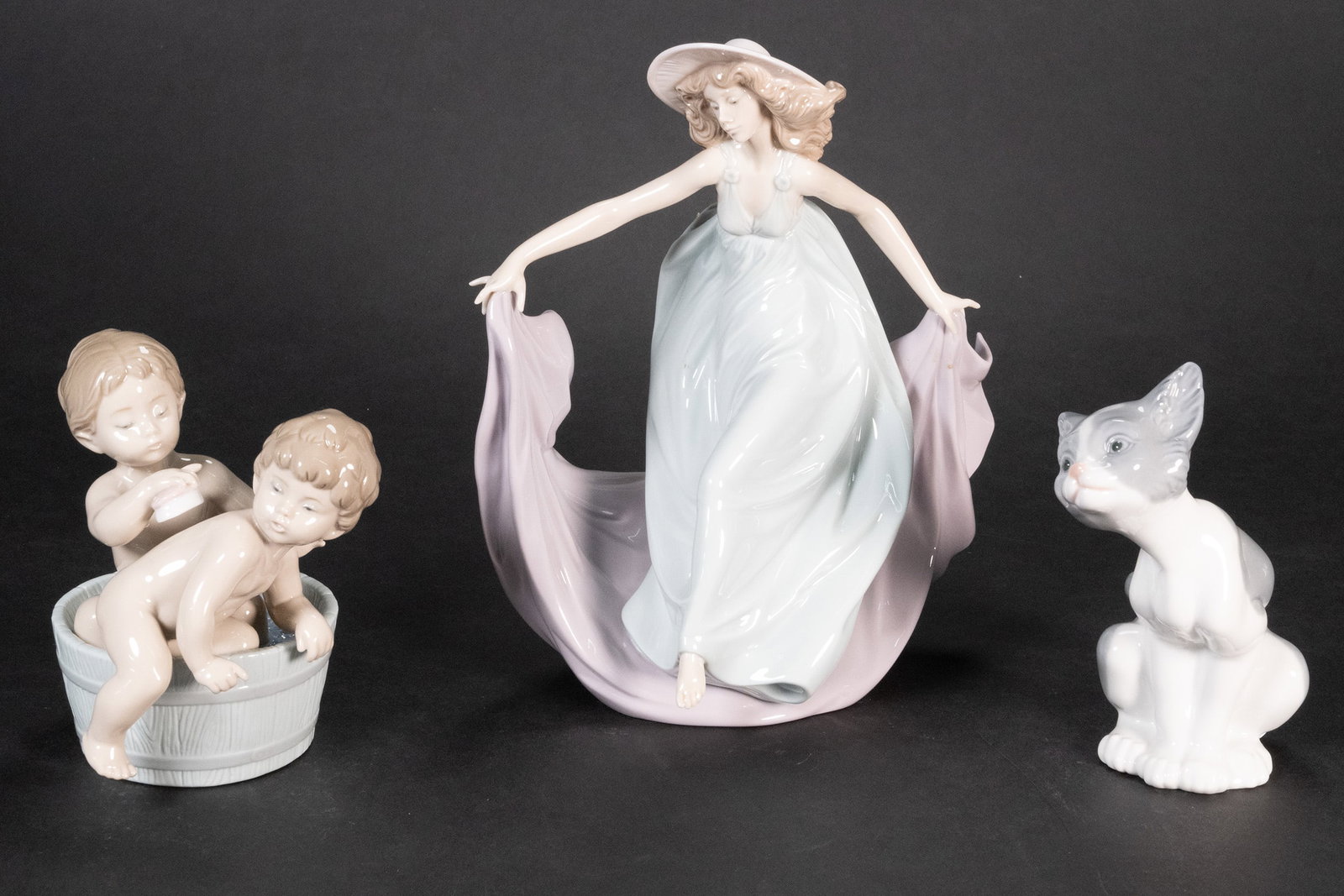 Lladro FigurineLot May Dance Kitten Feed Me and Bath Time: Lladro Figurines Grouping Group Lot May Dance Kitten Feed Me and Bath Time. May Dance Stands 9" Tall Wearing a Light Blue Dress Lavender Cape and Light Tan Hat. Kitten Feed Me Is 6" Tall Grey and Whit