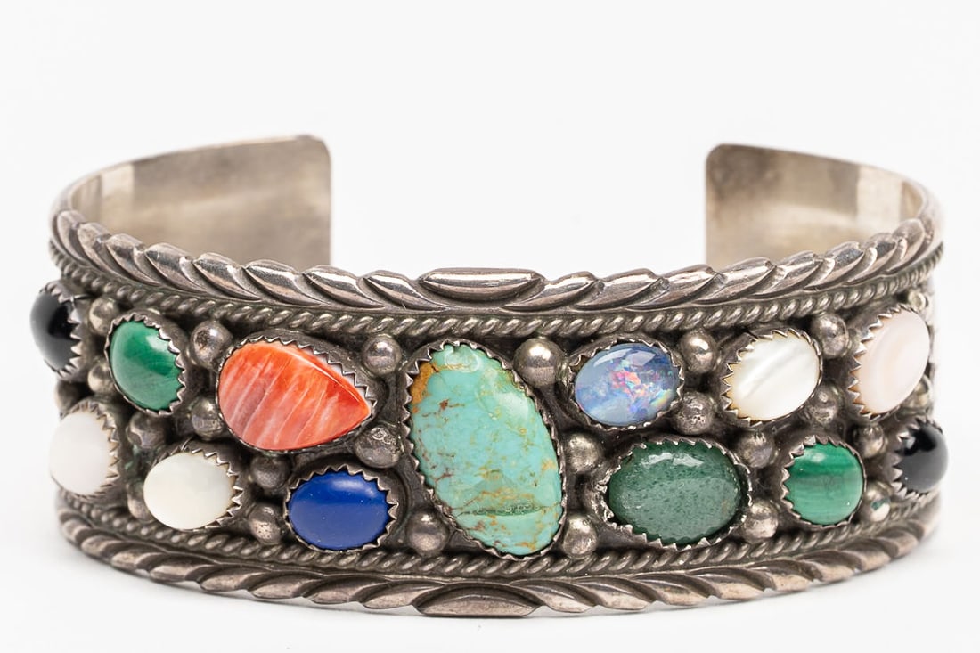 Richard Begay ( Navajo 1942 2013) Native American Wide Sterling Silver Multi Stone Cuff Bracelet: Richard Begay ( Navajo Tribe Native American 1942 - 2013 ) Wide Sterling Silver Multi Stone Cuff Bangle Bracelet Hallmark to Interior: " RB Sterling " Saw Teeth Bezel Set Gemstones such as: Royston Tu