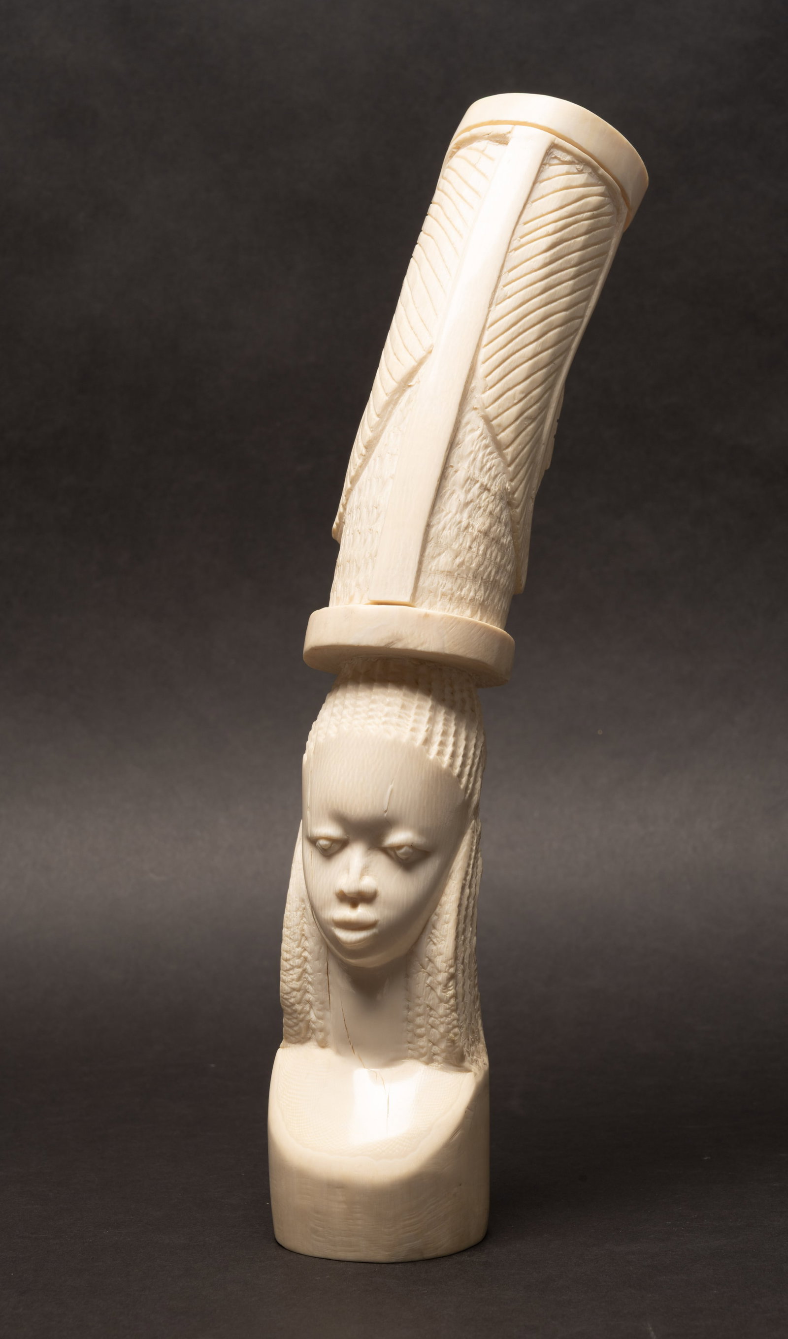 African Hand Carved Bone Female Figural Head Sculpture Vase: African Hand Carved Bone Female Bust Figural Head Statue Vase Circa Highly Detailed Carved in Relief Elongated Neck and Braided Coiffure Features a Serene Expression Supporting Cylindrical Vessel on H