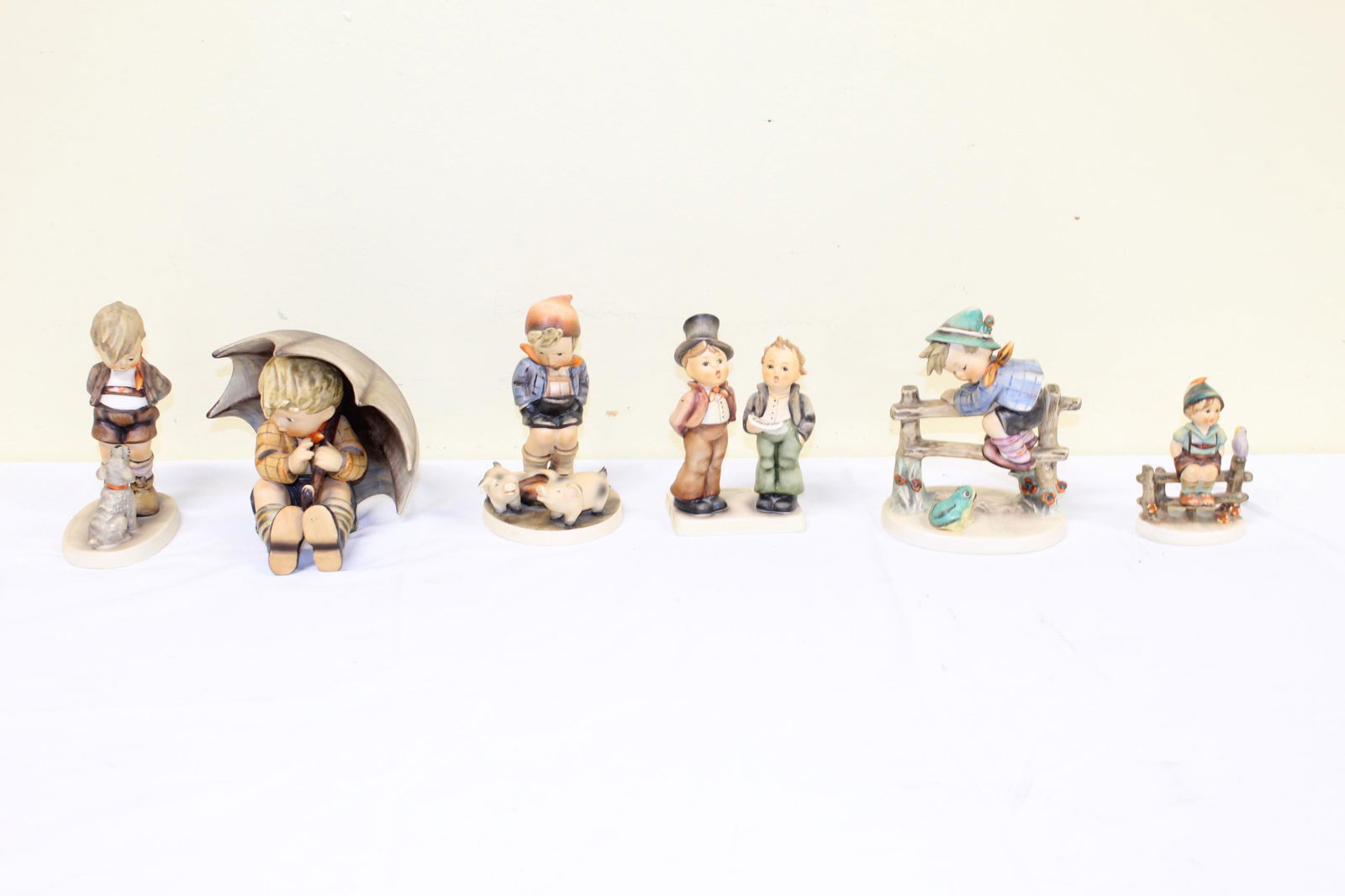Lot of Goebel Hummels: This nice lot includes 6 hummels. Labeled as; Boy sitting on a fence with bird next to him embossed on bottom 111 3/0 1938 and 55 â€“ measures 3.75in T overall. Two boys singing embossed on botto