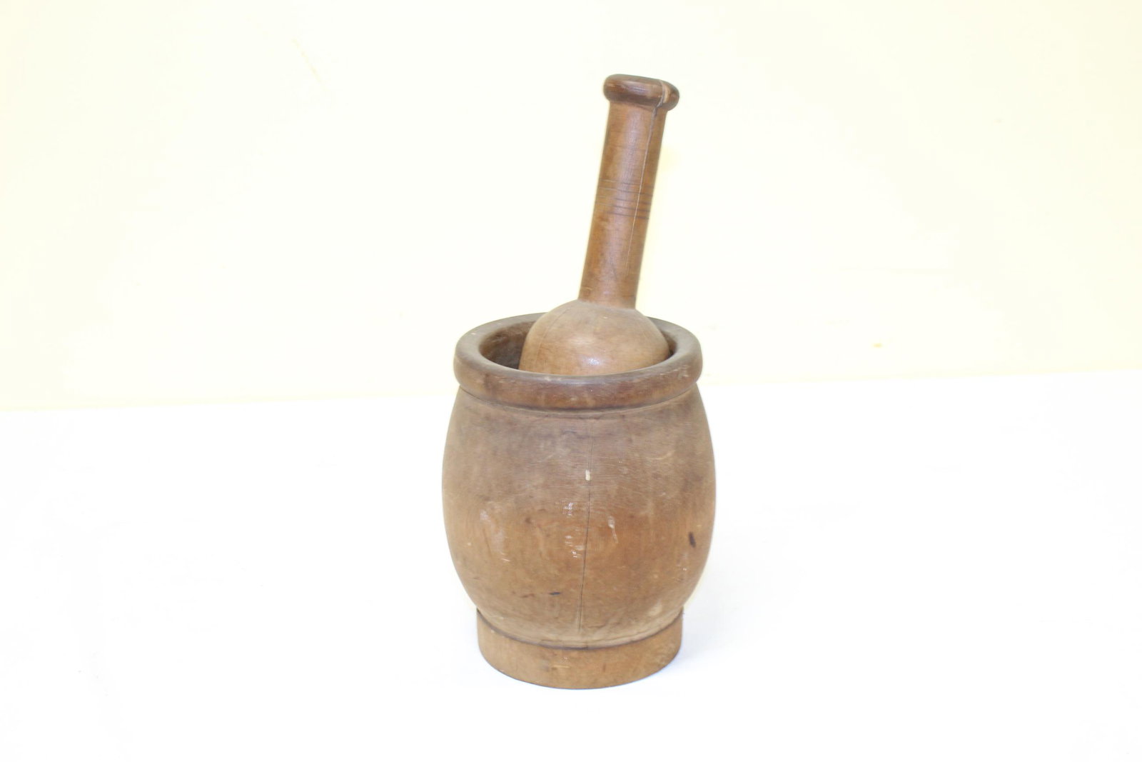 Large vintage wooden mortar and pestle: This large mortar measures 7.25in T x 5.25in R overall. The pestle measures 10in L overall. The pestle has a crack on one side that goes into the handle. The mortar also has a crack about 5.5in on one