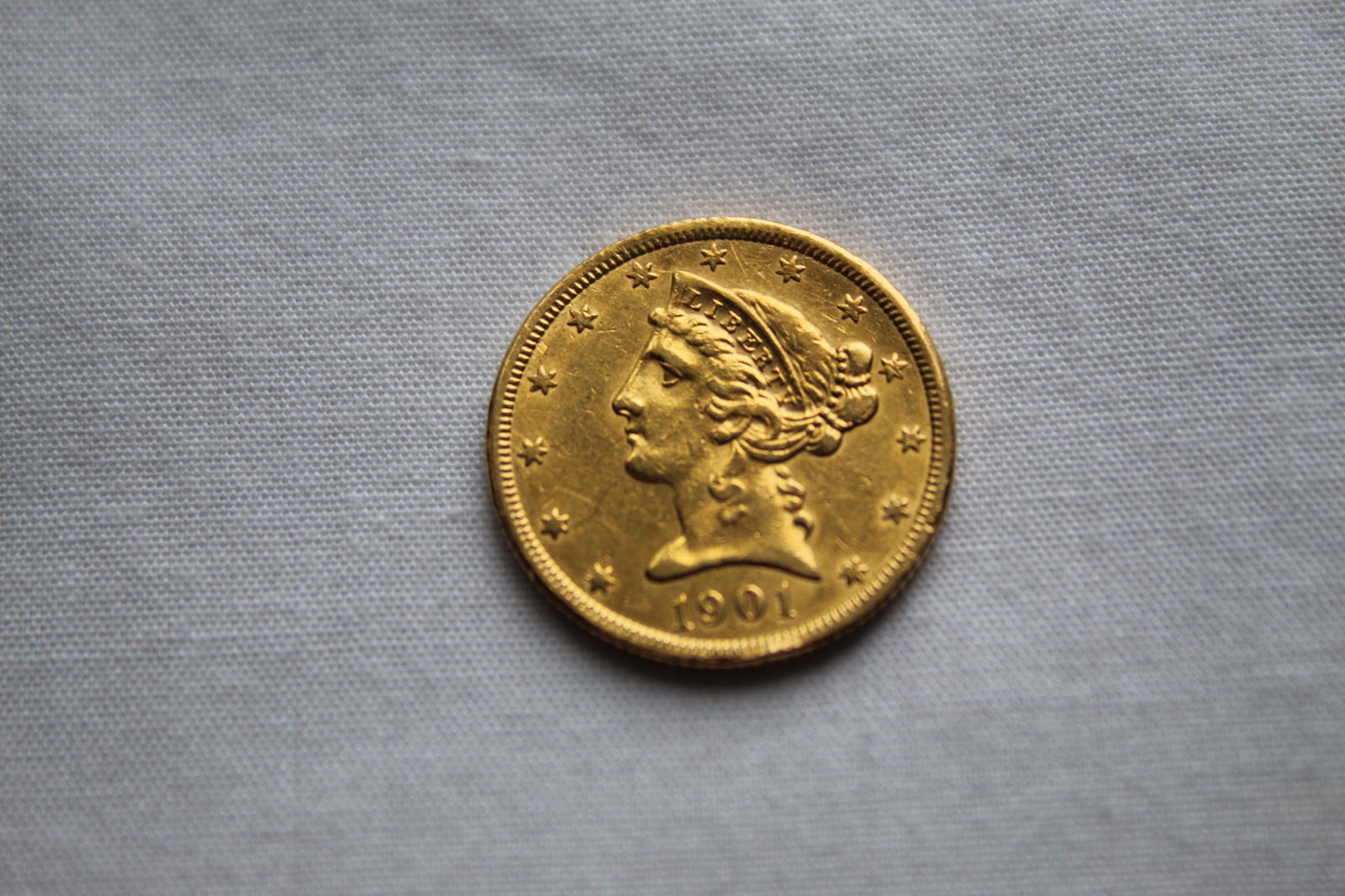 Liberty Head $5 1901-S Gold Coin: This antique Five Dollar Liberty Head Coin features a left facing Lady Liberty profile on the obverse with 13 stars circling the coin and the year of the minting on the bottom. On the reverse it has a