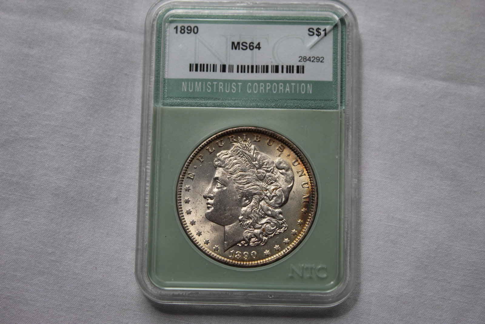 Graded 1890 MS64 Morgan Dollar: This 1890 $1 Dollar Coin is graded by NTC as 1890 MS64 Morgan $1 Coin. It is designed by George T Morgan and is composed of silver 0.9000 measuring 38.1mm in diameter and weighing 26.7300g. As always 