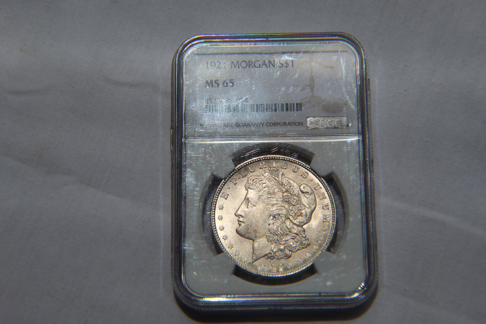 Graded 1921 MS 65 Morgan Dollar: This 1921 $1 Dollar Coin is graded by NGC as 1921 MS 65 Morgan $1 Coin. It is designed by George T Morgan and is composed of silver 0.9000 measuring 38.1mm in diameter and weighing 26.7300g. Interesti