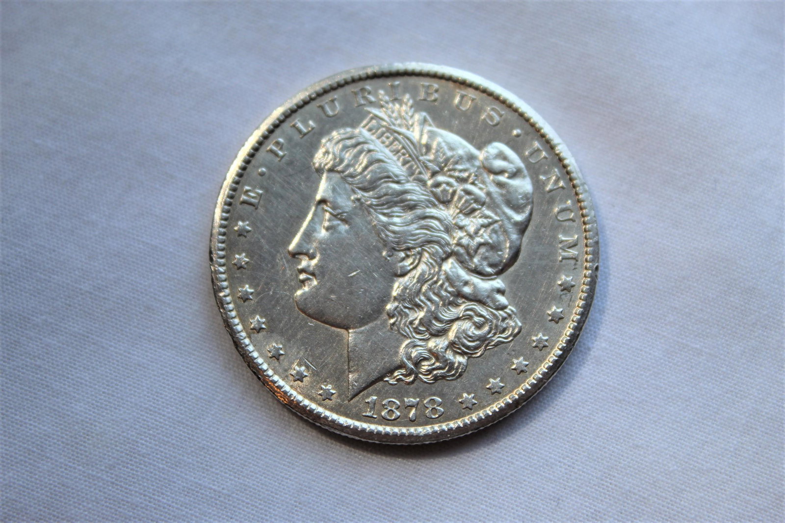 1878-CC Morgan Dollar: This 1878 Carson City $1 Morgan coin was designed by George T Morgan and is composed of silver 0.9000 measuring 38.1mm in diameter and weighing 26.7300g. 1878 marked the first year of production for t