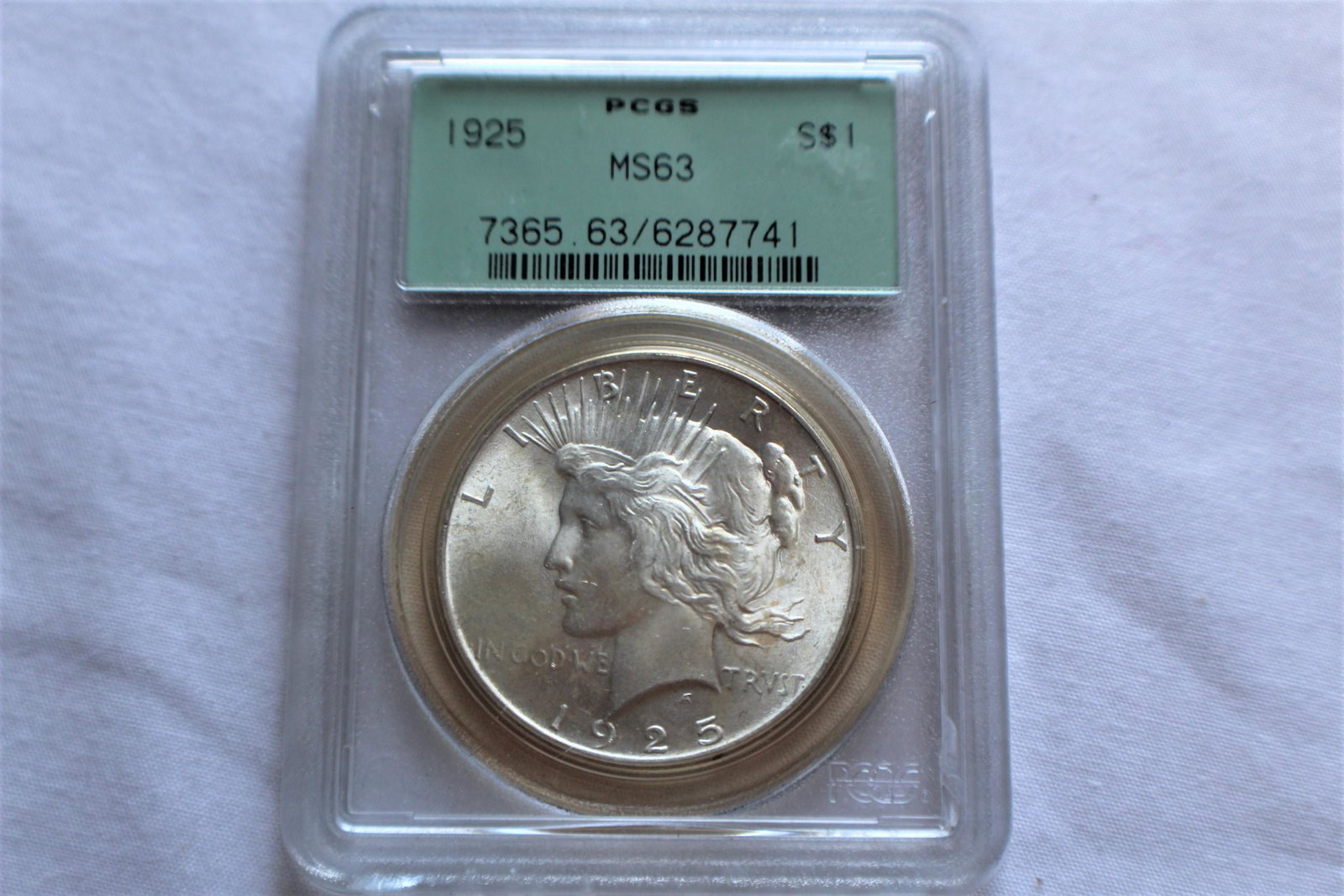Graded 1925 MS63 Peace Dollar: This 1925 Peace Dollar is graded by PCGS as 1925 MS63 $1. A 1925 Peace Dollar was designed by Anthony de Francisco and is composed of silver 0.9000 measuring 38.1mm in diameter and weighing 26.7300g a