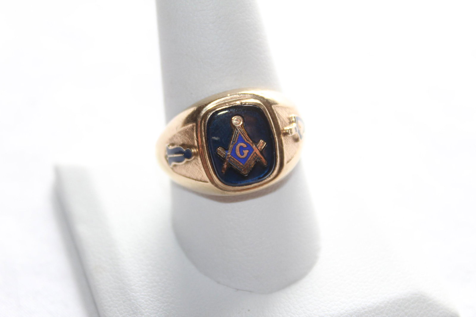 6.5 Gram 10K Gold Freemasonry Size 10.75 Men's Ring: This masculine ring features a blue stone, center, along with the square and compass Freemasonrys Logo. There is also a small design on either side, as pictured. The ring is marked 10K 3HD 484 on the 