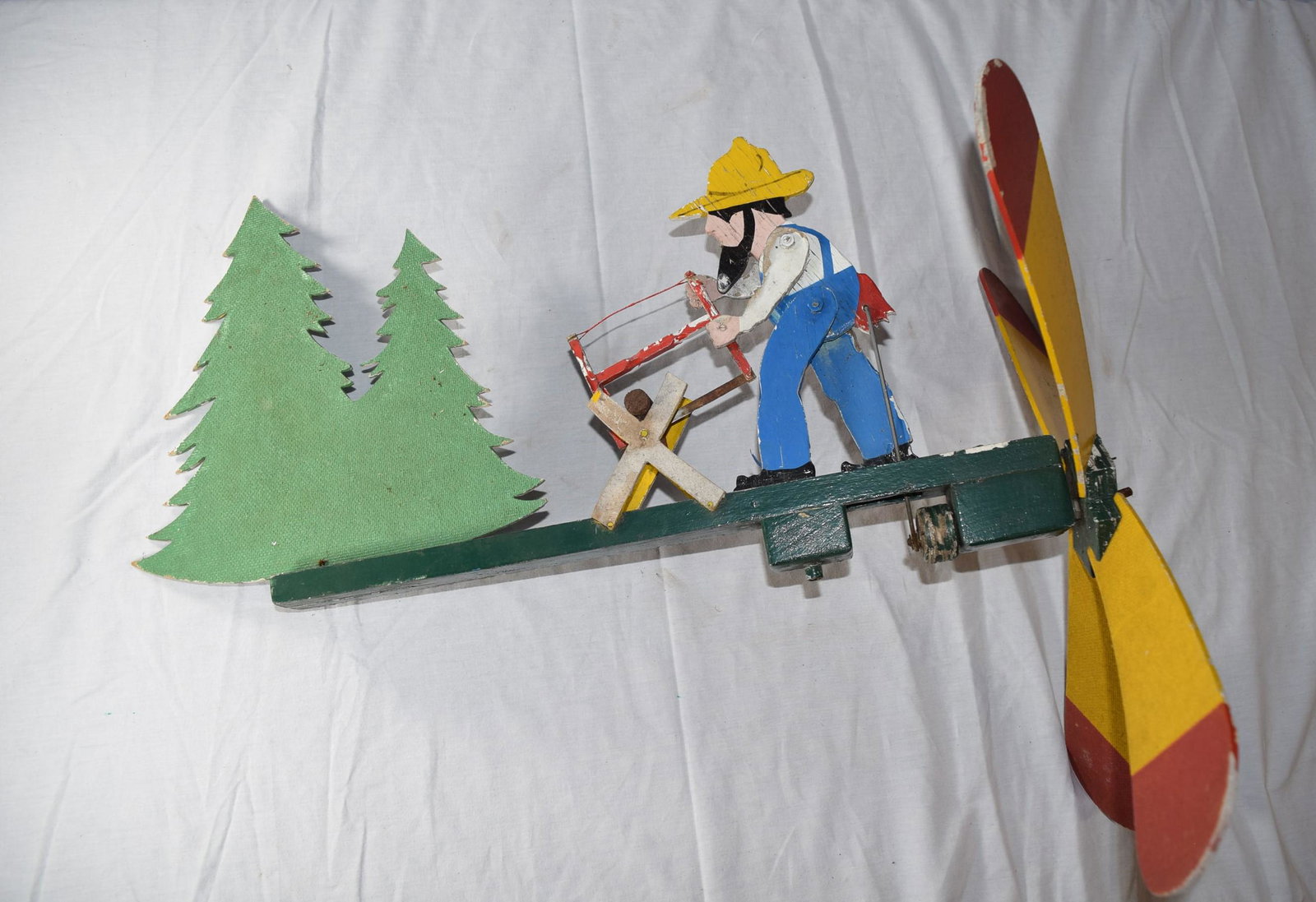Early Painted Woodman's Whirligig: Early Painted Whirligig depicting a lumberjack cutting a log in the woods. The whirligig does have paint loss on either side as shown and measures 24.25 inches long from tip to tip with the propellers