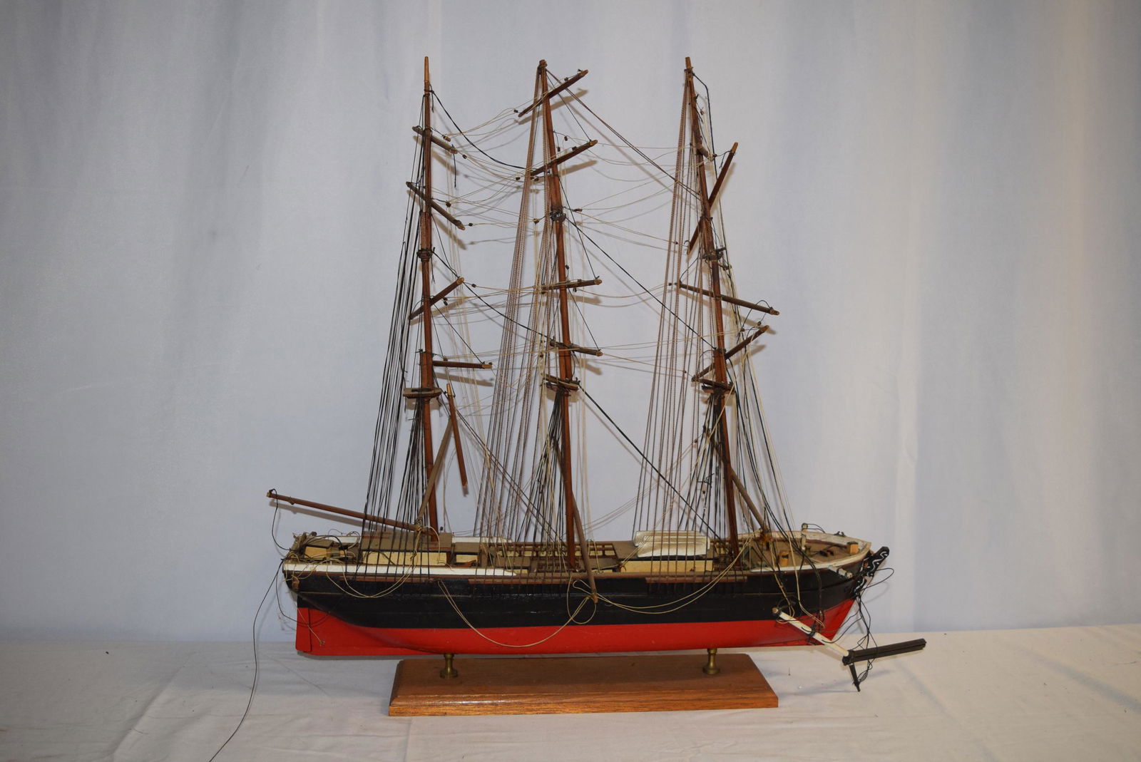 Wooden Painted Ship Model On Stand: Wooden Painted Ship Model mounted on stand, features black and red painted hull, named "Susan". Measures 26.5 inches tall overall X 25 inches long overall X 9 inches at its widest point, hull itself m
