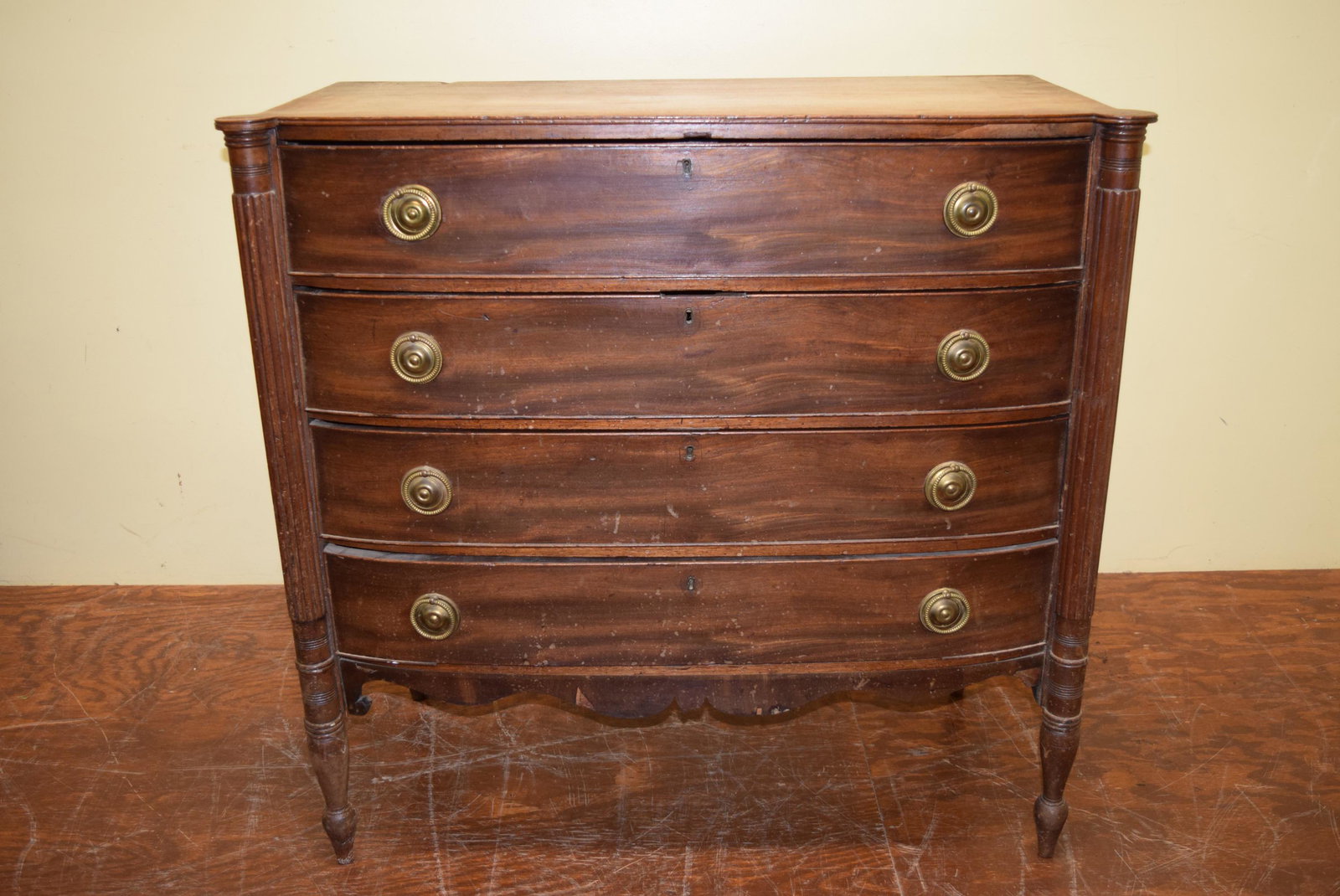 Antique Four Drawer Bow Front Chest: This beautiful bow front chest features cookie cornered reeded columns on the front and brass pulls. Dove tail construction drawers. Drawers measure 6in T. Will need to be refinished. Circa 1800s. Mea