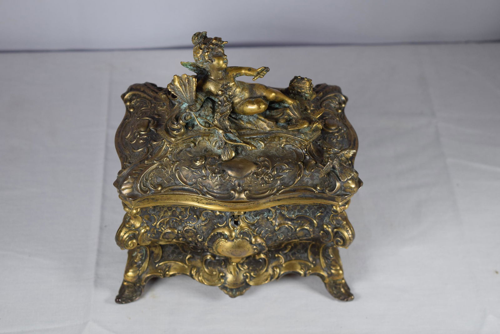 Vintage Ornate Gold Metal Keepsake Box: Vintage ornate keepsake box features on the lid a cherub with birds and other decoration. Box is heavily decorated. Interior features mirror and red velvet lined. This is missing the key. Slight oxida