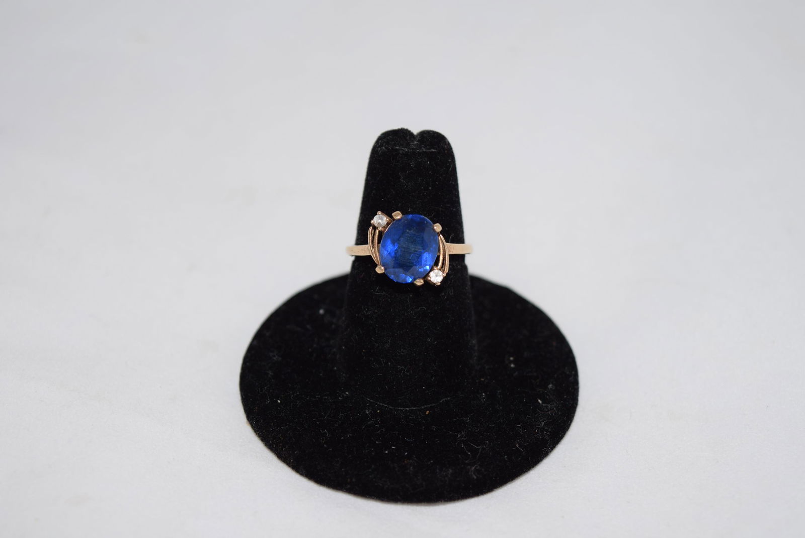 Ladies 10K Gold Ring: This beautiful ring features a synthetic blue stone with cubic zirconia on either side. This is a size 6 and weighs 2.8 grams. Marked 10k on the band. Overall in nice condition with no damage or repai