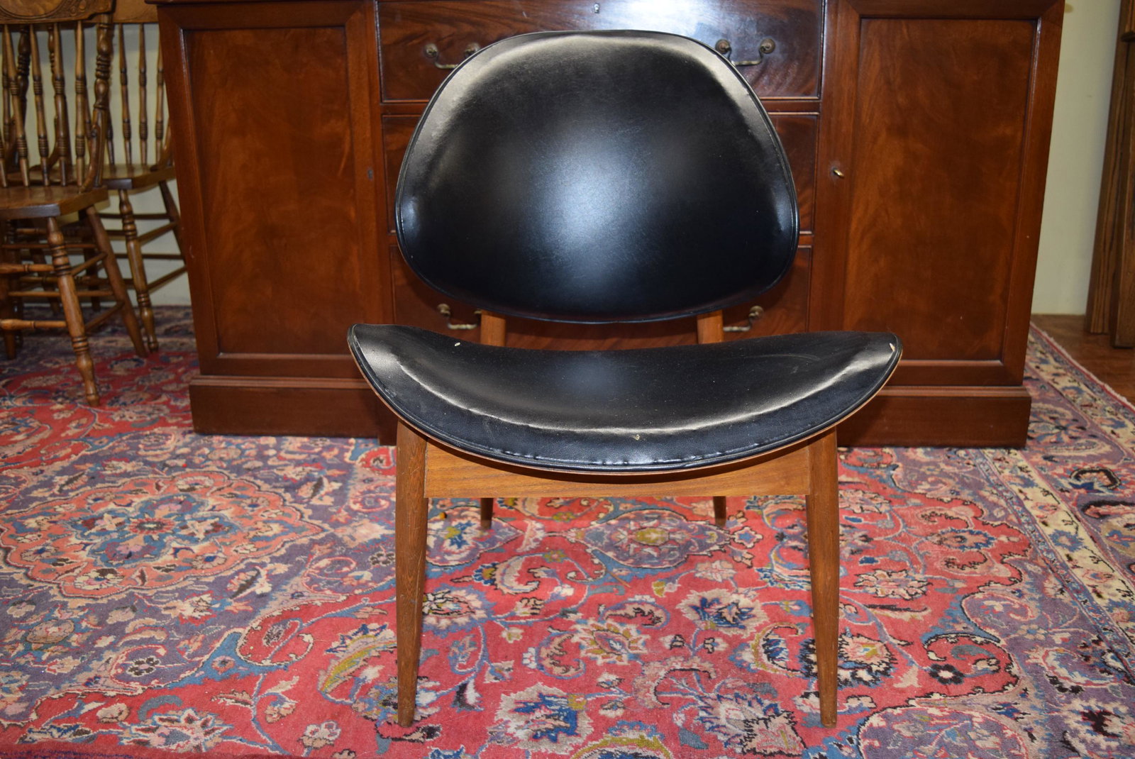 Mid Century Modern Black Leather Chair: Beautiful shaped mid century modern black leather chair measures 30.25in T x 22in W x 23in D x 15in T floor to seat. There is a small rip in two places on the seat otherwise in great overall condition