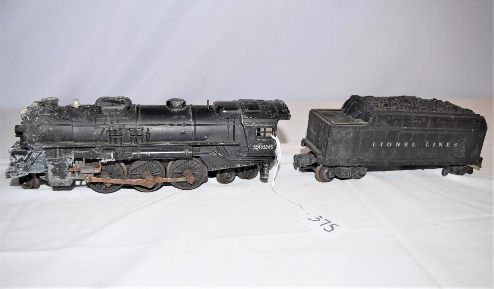Vintage Lionel Lines 2026 Engine and Tender: Lot includes Lionel Lines 2026 engine with 2466WX coal tender. There is some oxidation on the engine and rust underneath on the wheels. These go together I believe however can not be sure. We are unab