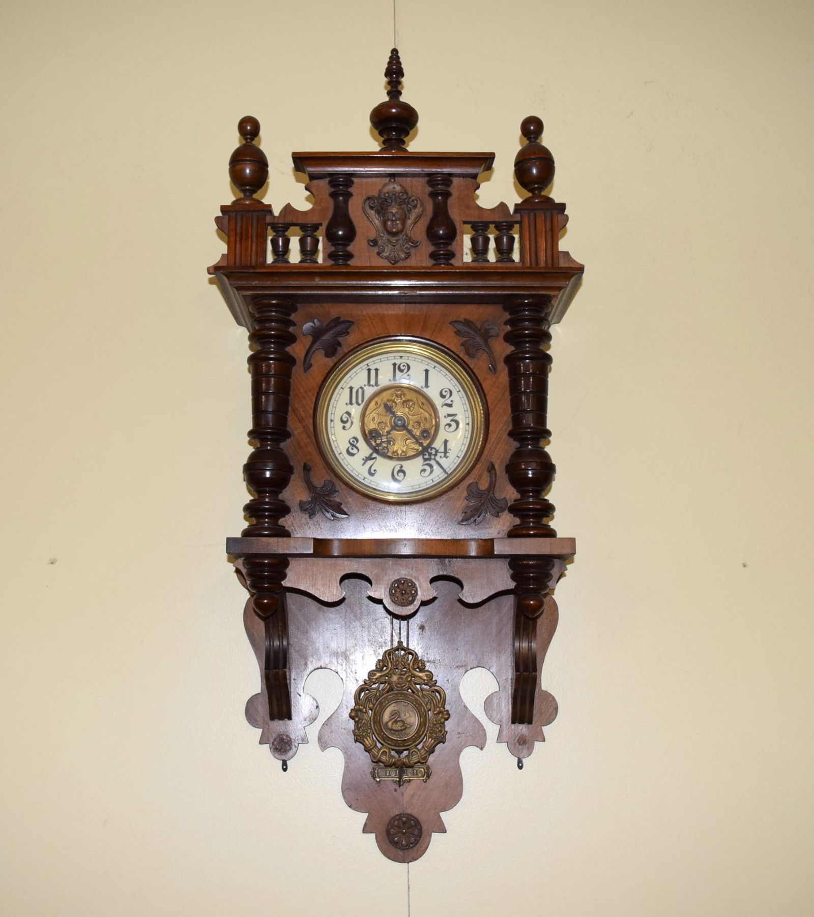 Gloria Grandmother German Wall Clock: Very Ornate Gloria Grandmother German Wall Clock features decorative detail from top to bottom! The darker shade of wood on the decoration give them more definition from the spindles, to the leaf deco