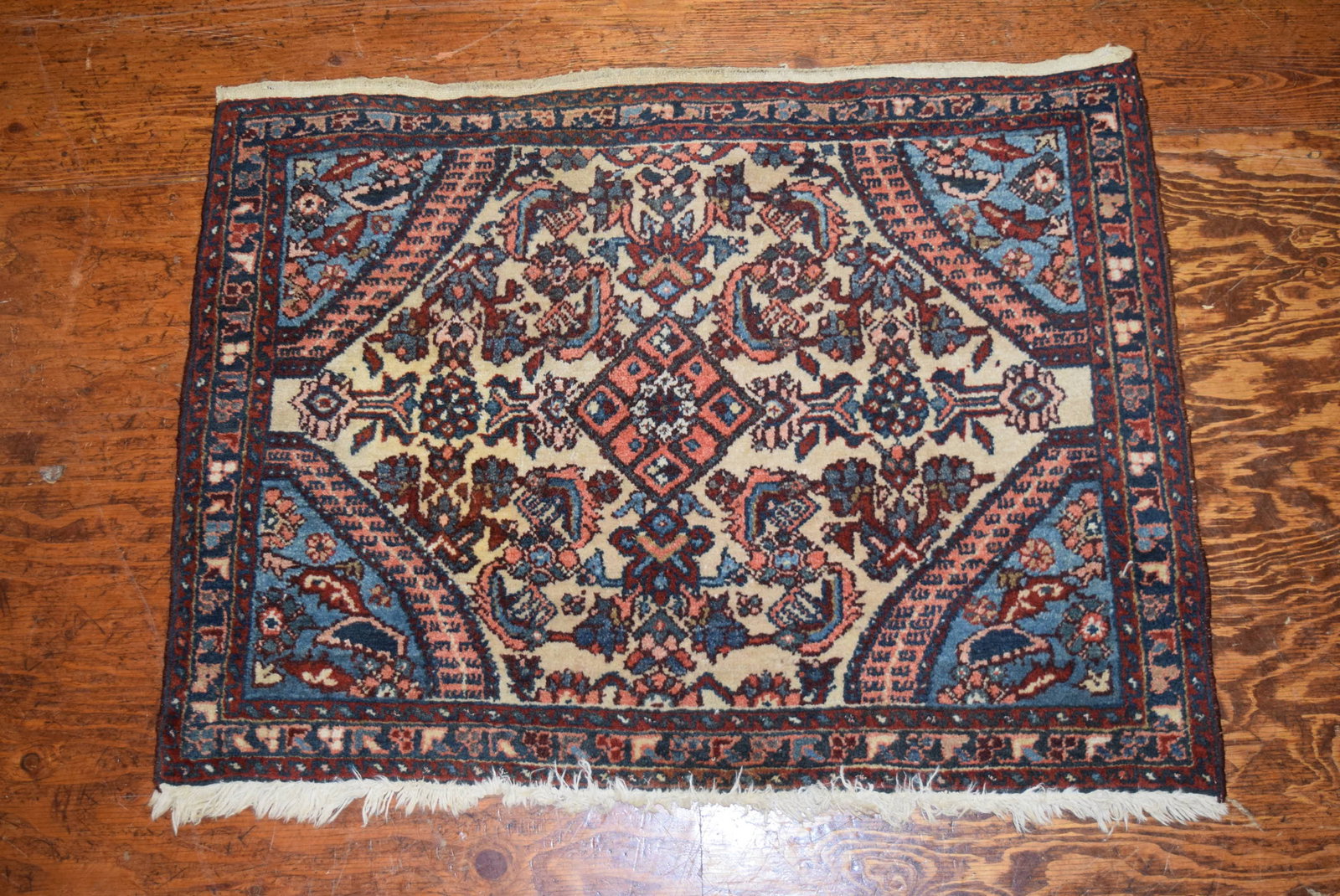 Small Antique Oriental Throw Rug: Small Antique Oriental Rug made in Iran. Tags still intact. Minimal wear for its age with slight staining. Features muted colors of peach, blue, reds and cream. Measures approximately 33 inches X 26 i