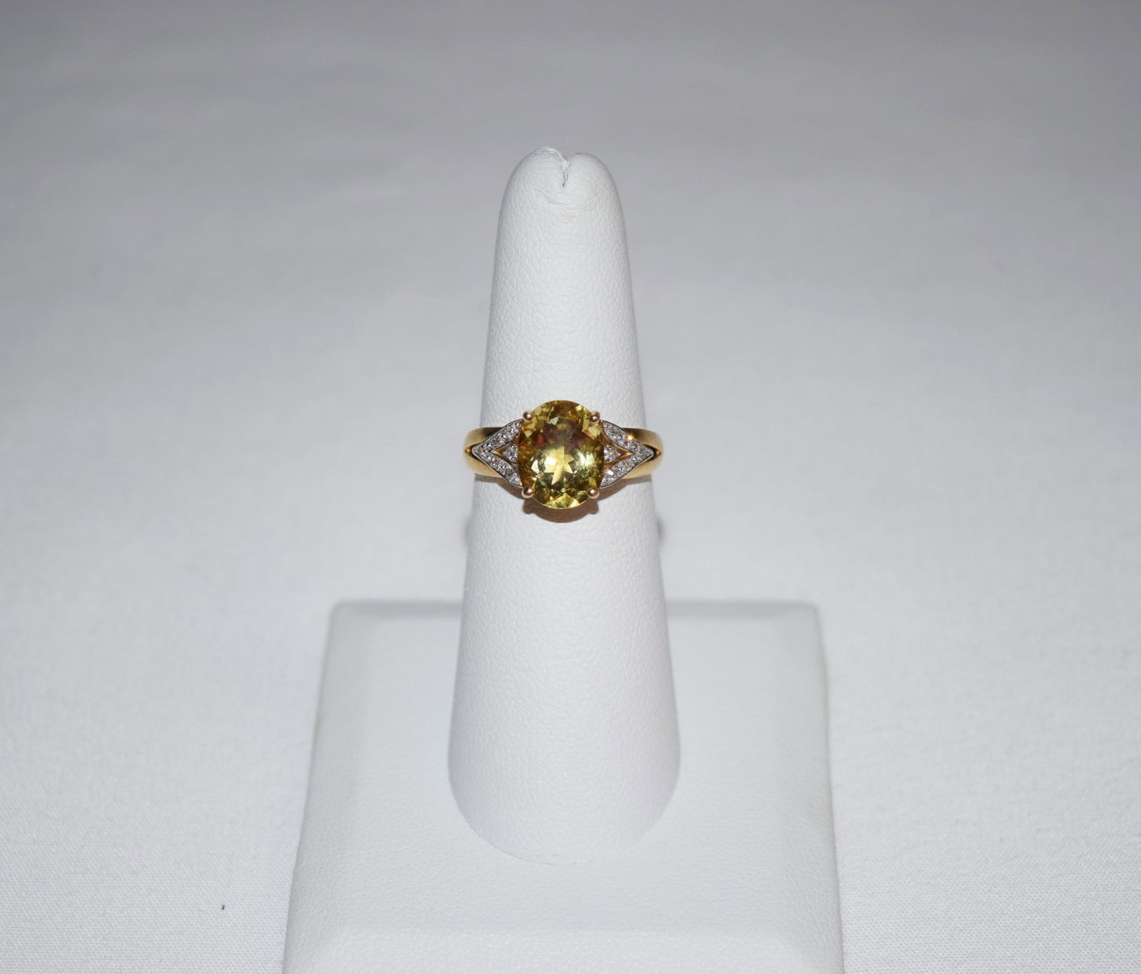 14K Yellow Gold Lemon Quartz Ladies Ring: 14K Two Toned Gold Ladies Ring that features a large oval cut lemon quartz stone in the center in a four prong setting. The band is a yellow gold with accents of small round cut clear stones on either