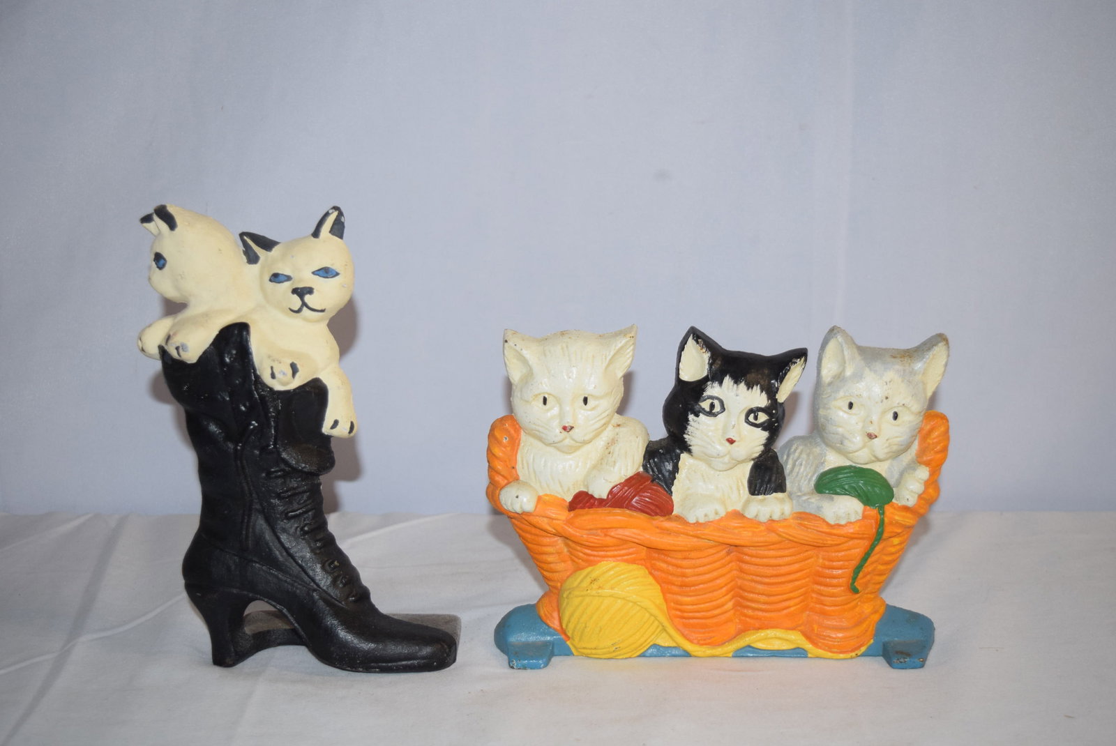 Lot of Two Cat Cast Iron Doorstops: Lot of Two Cat Cast Iron Doorstops. The two cats in the boot measure 9.25 inches tall X 5 inches wide X 3 inches deep. The three cats in the basket measure 6.5 inches tall X 9 inches wide X 2 inches d