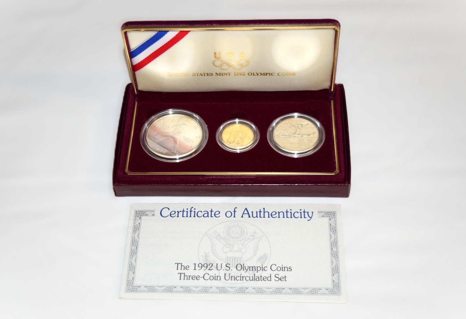 1992 US Olympic Three Coin Uncirculated Set: United States Mint 1992 US Olympic Three Coin Uncirculated Set comes with a Certificate of Authenticity. Set includes a Gold Five Dollar Coin, a Silver Dollar Coin, and a Clad Half Dollar Coin, all in