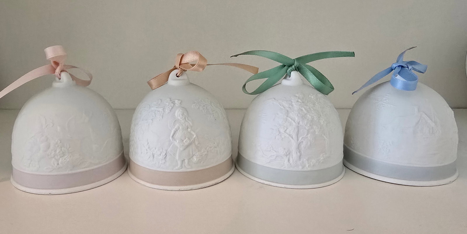 Four Lladró Porcelain Collector Bells: ITEM DESCRIPTION Maker: Lladró, Spain Description: Group of four Lladró porcelain collector bells, each decorated with a different delicate figural and floral motif in Lladró's characteristic soft 