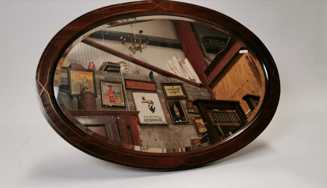 Edwardian oval mirror.: Edwardian oval mahogany mirror inlaid with brass. { 70cm H X 101cm W }.
