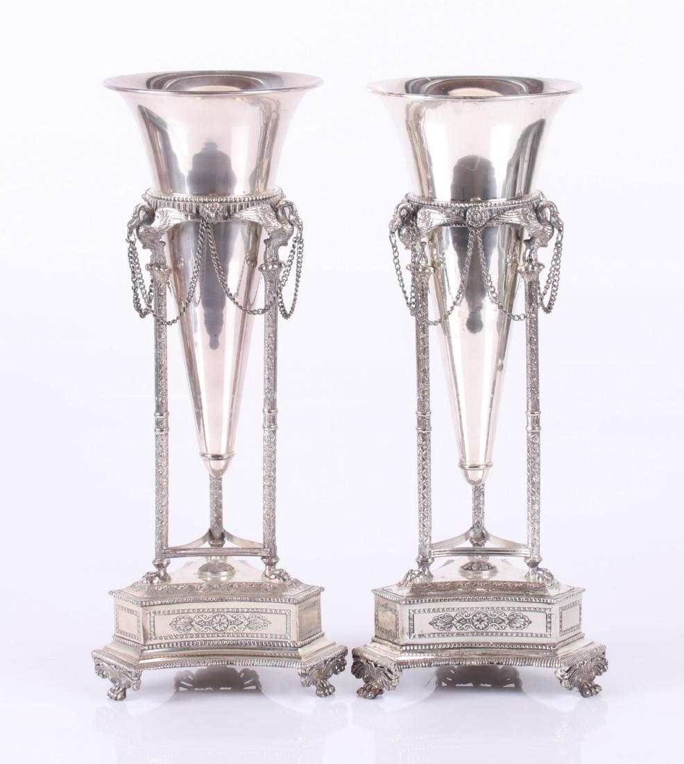 A Pair of Silver Plated Regency Style Vases: 20th century, each with three paw feet below three legs which terminate with swans with chained swags. The trumpet vases feature liners. Dimensions: Each is 8" in diameter and 16 1/2" tall. Provenance