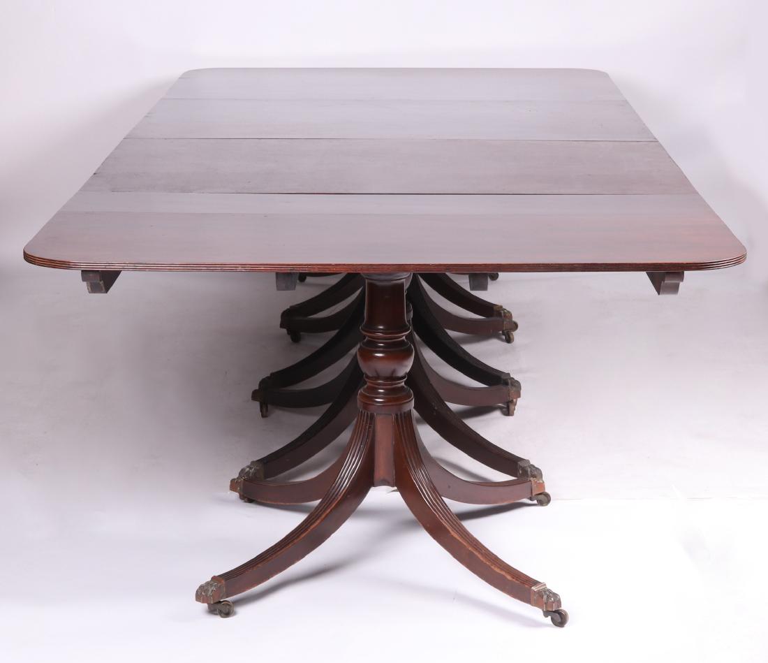 19th C. English Mahogany Four Pedestal Dining Table: Each of the four pedestals feature casters, cast brass paw feet, reeded legs, and a turned shaft. The top features rounded corners and a reeded edge. Includes three leaves as pictured. Dimensions: 119