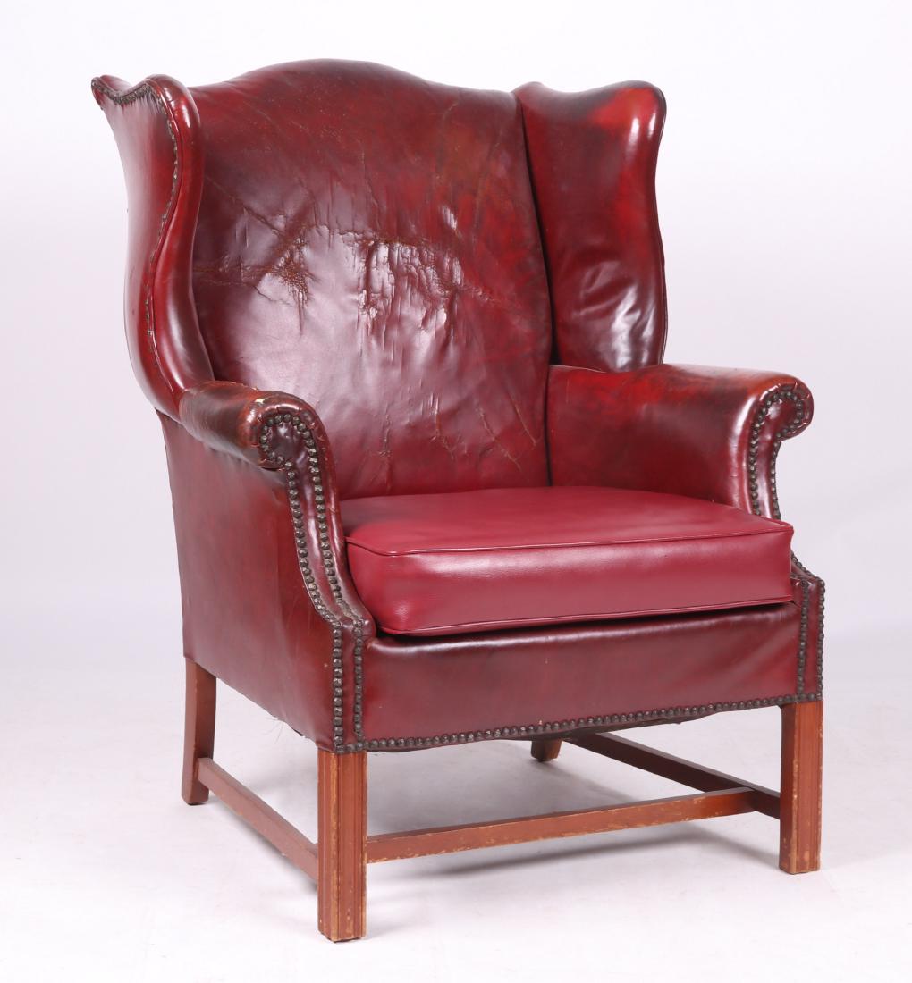 Chippendale Style Leather Wingback Chair: 20th century. With square molded legs, box stretchers, red leather covering, and brass tacks at the arms. Dimensions: 33" arm to arm, 25" deep, seat height of 18 3/4", overall height of 40". Provenanc