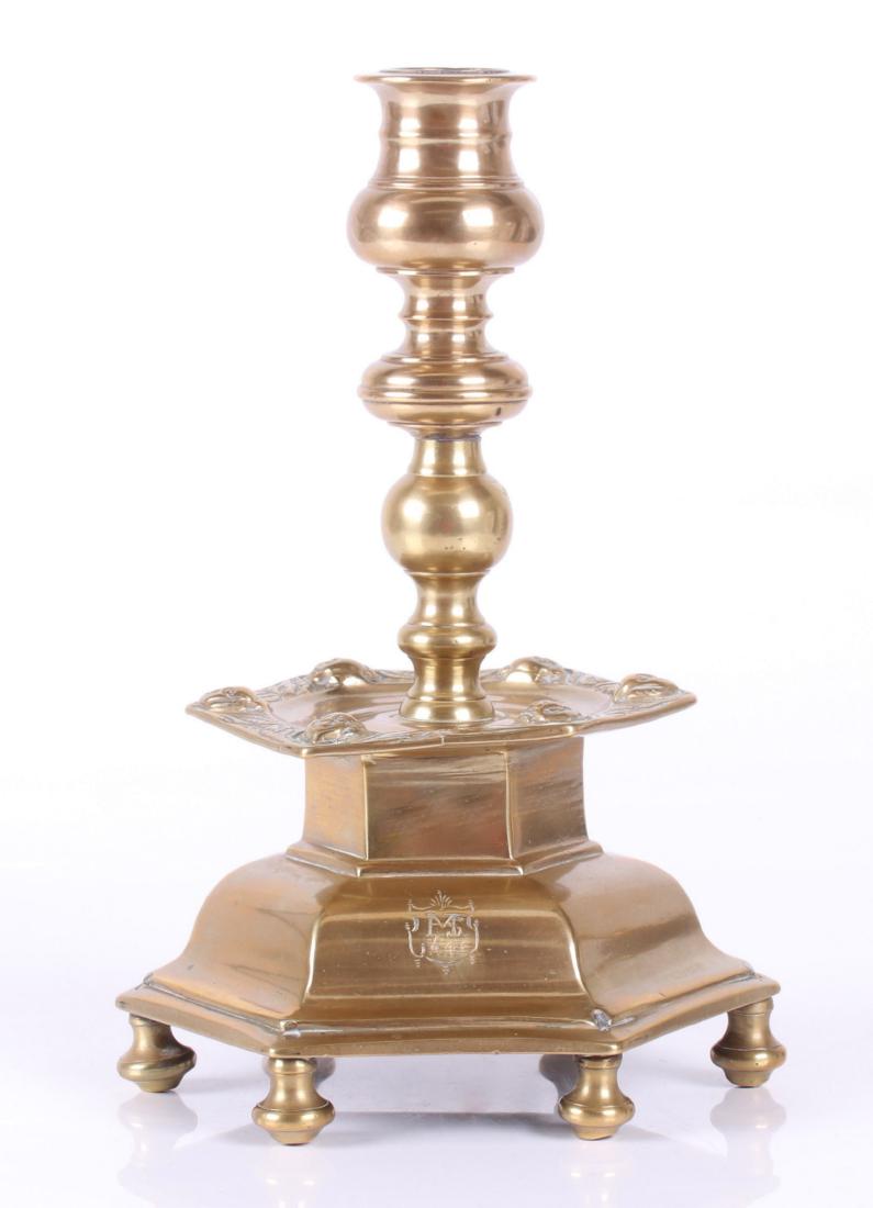 A 17th Century Scandinavian Brass Candlestick: Hexagonal, with short feet, a molded base, mask decorated drip pan and a turned shaft and nozzle. Dated 1645 as pictured. Dimensions: 8" in diameter, 11" tall. Provenance: From a local estate.