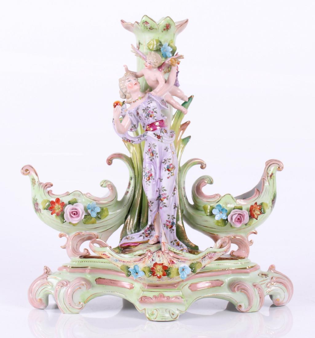 A Continental Porcelain Epergne: Late 19th century, rococo in style with central figures,three receptacles and a candlestick. Dimensions: 13 1/2" x 9", 13 1/2" tall. Provenance: From a Philadelphia estate.