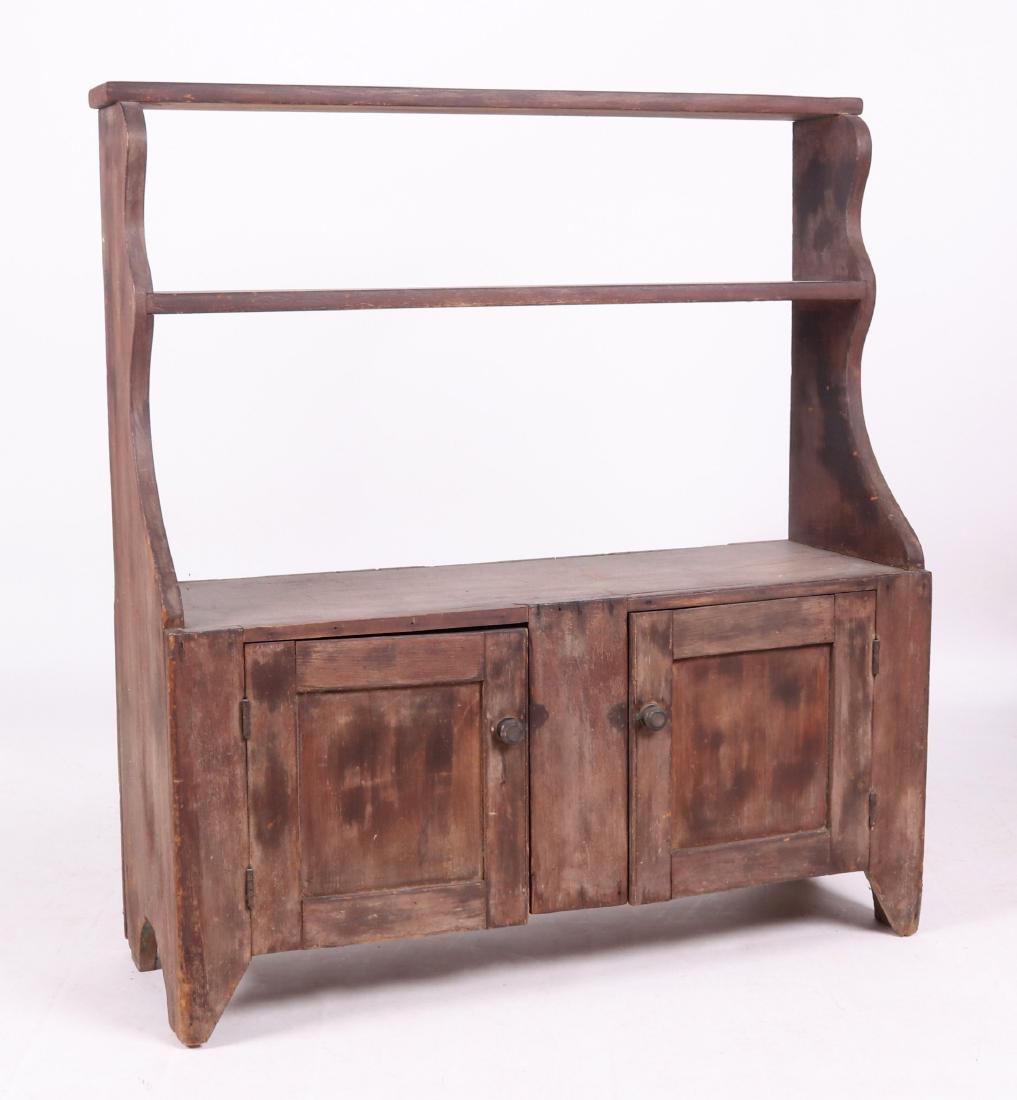 A 19th Century American Bucket Bench: With cut bracket feet, two paneled doors, scalloped sides, and two shelves. Dimensions: 40 1/2" x 14 1/4", 45" in overall height. Provenance: From a local estate.
