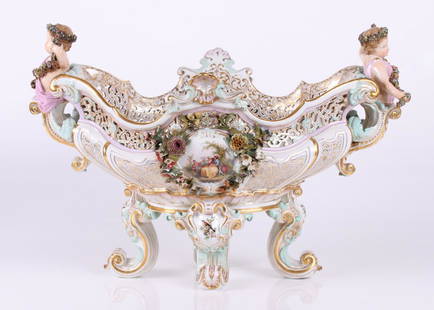 A Monumental Meissen Centerpiece: 19th century, a Rococo style piece with four scrolled feet below bird decorated knees below a body with reserves decorated with figures surrounded by encrusted flowers below an elaborately