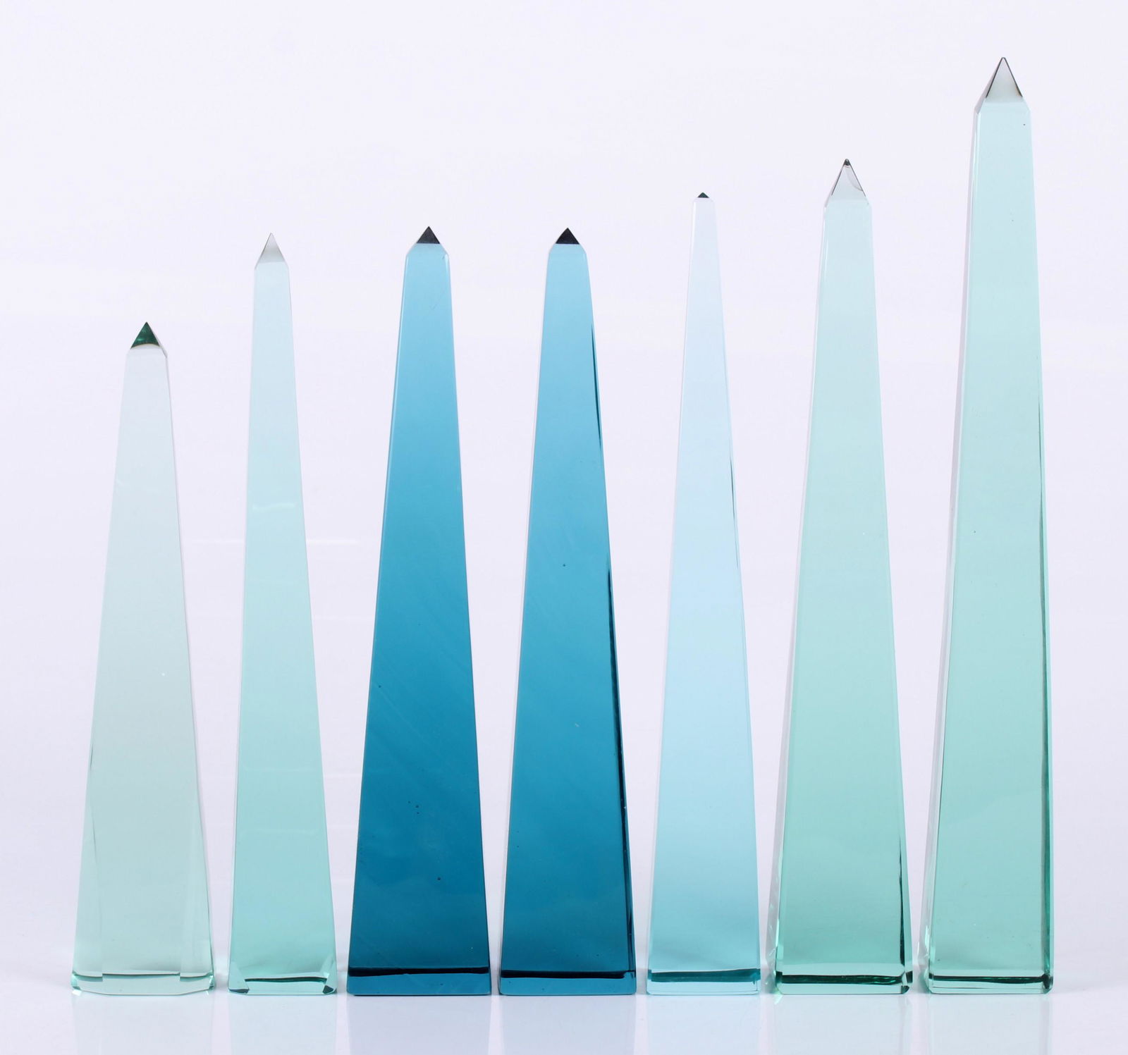 Seven Glass Obelisks: 20th century, none signed, two in blue and five are green. Dimensions: From 2" x 2" to 2 1/4" x 2 1/4", the heights range from 10 1/4" to 14 1/2".