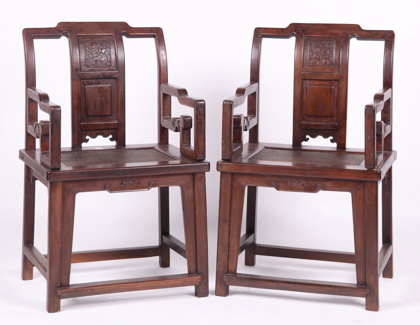 Pair of Chinese Export Rosewood Armchairs: 20th century. Each with box form stretchers, square canted legs, below a caned seat, scrolled arms, and a rectangular stepped back centered by a carved splat. Dimensions: Each is 22" wide, 17 1/2" dee