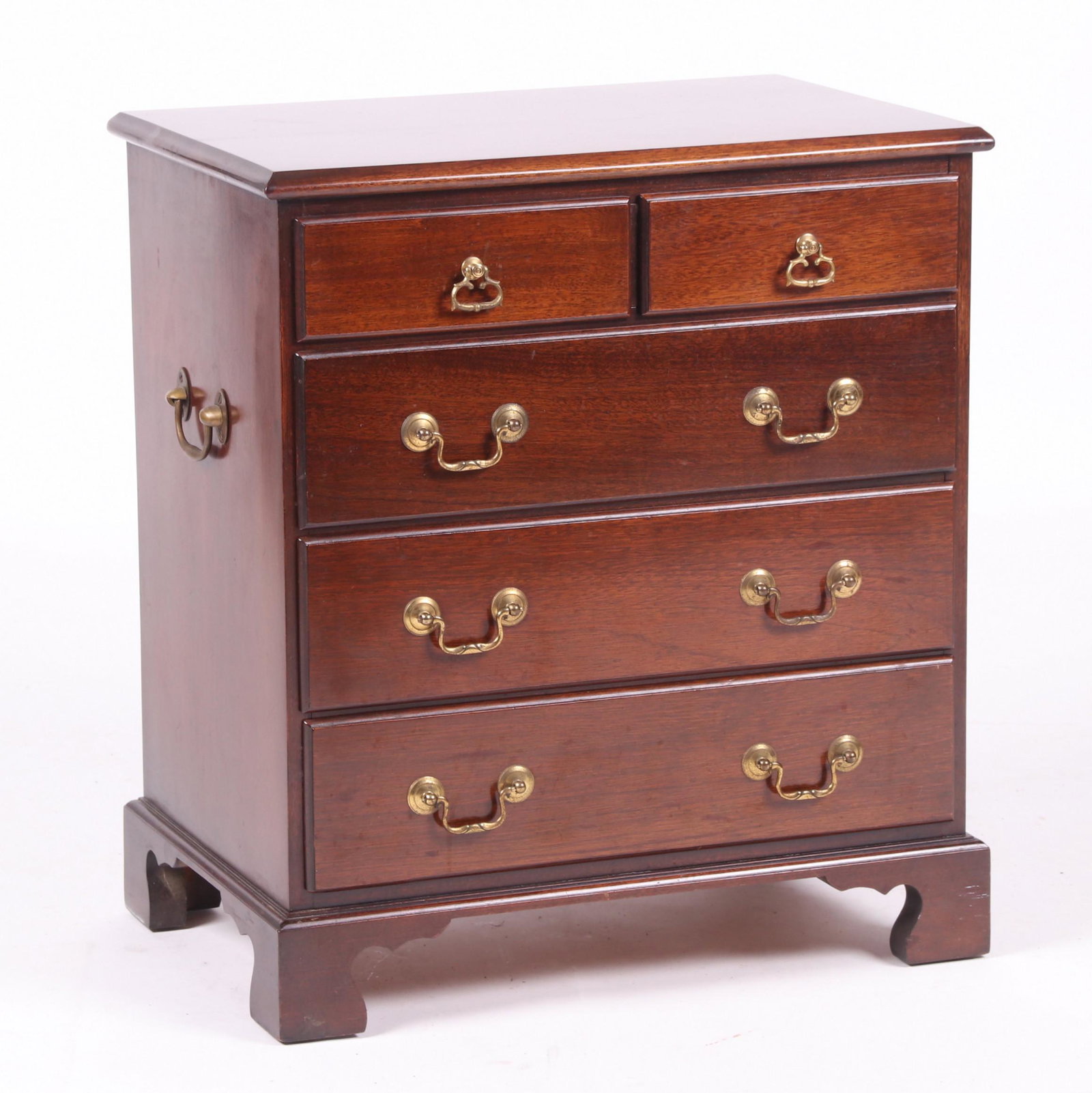 Georgian Style Miniature Mahogany Chest of Drawers: 20th century. With straight bracket feet below three long drawers which are fitted with bail and rosette hardware, below two short drawers with stirrup pulls, all below the conforming molded rectangul