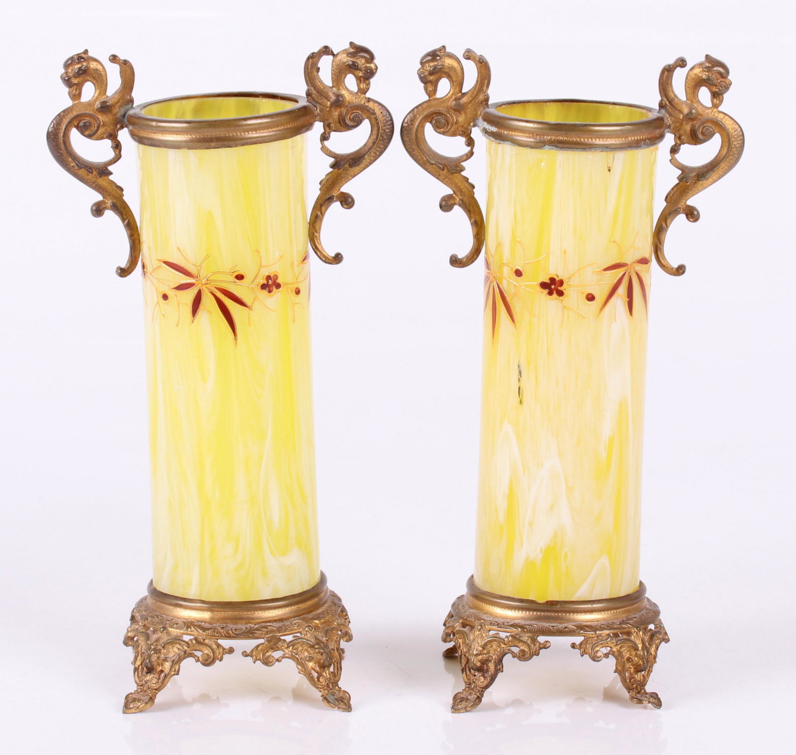 A Pair of Ormolu Mounted Glass Bud Vases: Late 19th century, each with four pierced and mask decorated feet below the mottled yellow and white glass body which features enameled decoration, all below griffin handles. Dimensions: Each is about