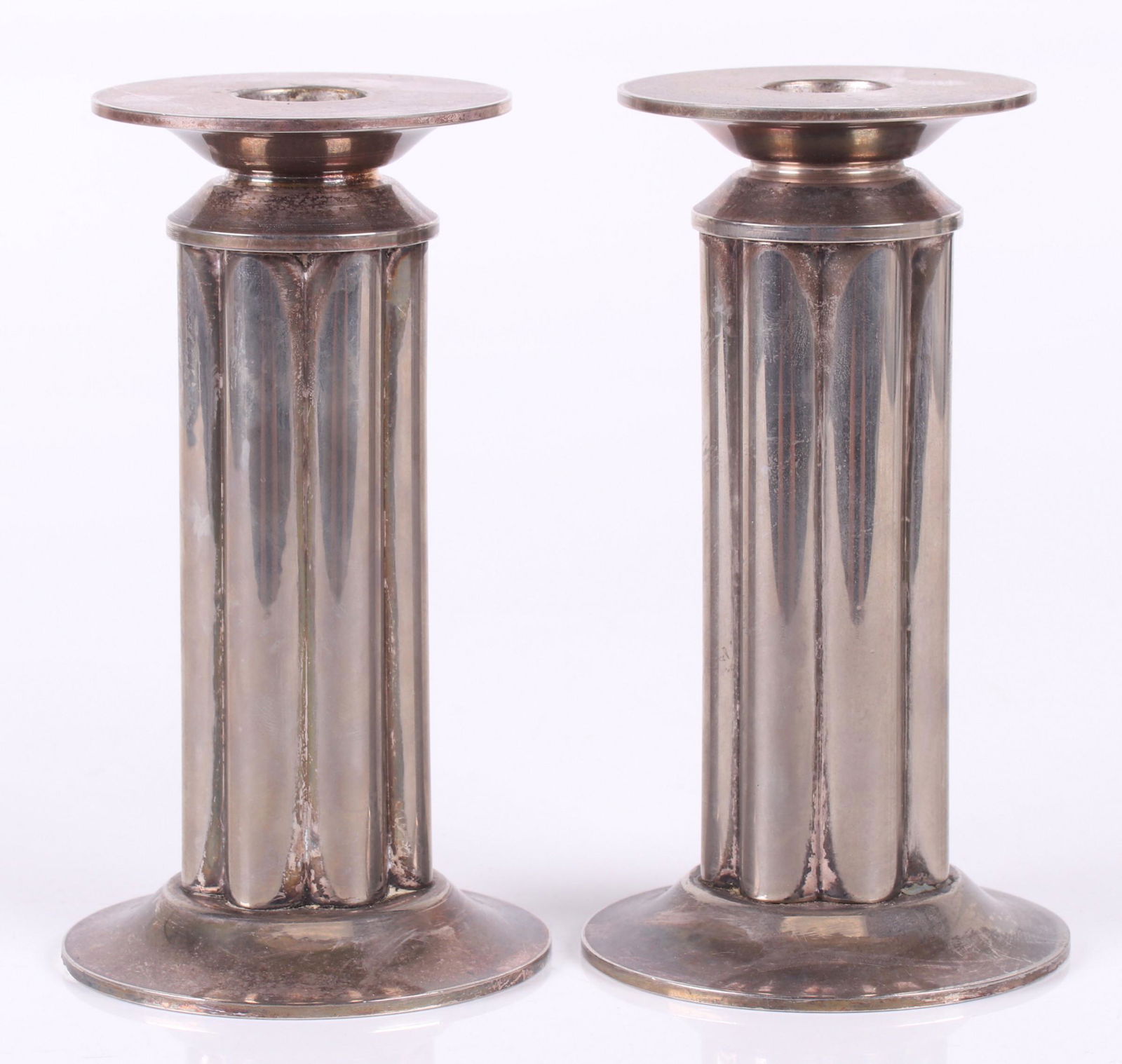 Pair of Candlesticks, Robert Stern for Swid Powell: Silver plated, each with a molded circular foot and a reeded shaft. Signed as pictured. Dimensions: Each is 3 1/2" in diameter and 6 1/4" tall. Provenance: From a Philadelphia estate.