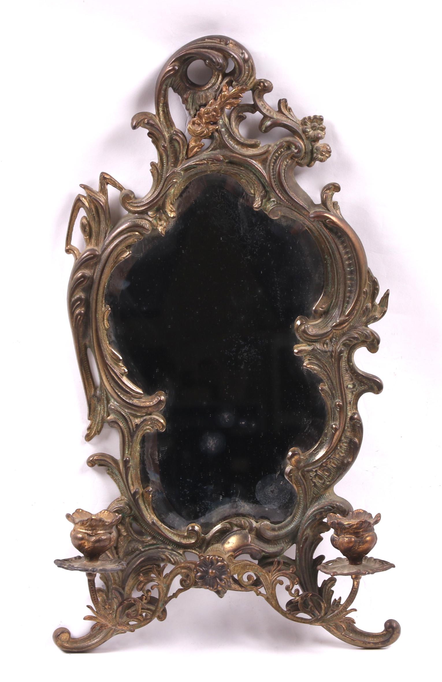 Rococo Mirror by National Brass & Iron Works: With scrolling acanthus, foliate, and floral decoration, and a two light sconce with bud form nozzles and central floral pendant, signed verso. Dimensions: 12" x 22", 3" deep.
