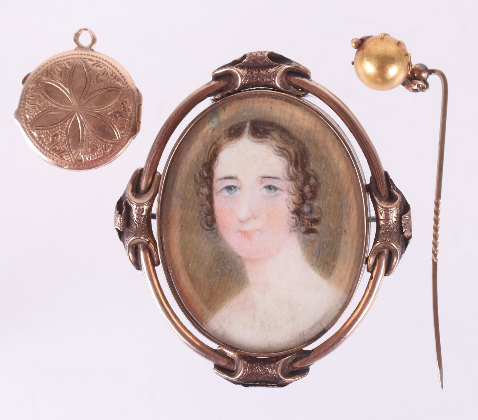 Three Pieces of Antique Gold Jewelry: A 10k gold framed mourning miniature pin/pendant, a watercolor portrait of a young woman, first half 19th century; a 14k gold locket with floral and scrolling decoration, 19th century; a 14k gold stic