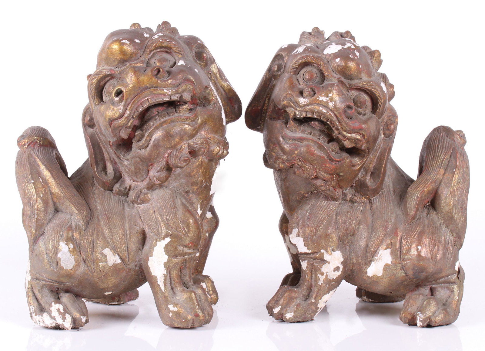 A Pair of Chinese Plaster Foo Dogs: 20th century, each with a gilt surface with traces of polychrome. Dimensions: Each is 9" x 8" and 13" tall. Provenance: From a local estate.